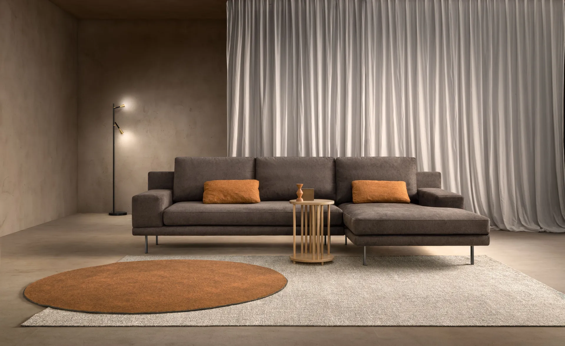 Divano Wise Samoa marrone con chaise longue e cuscini arancioni, su tappeto tondo