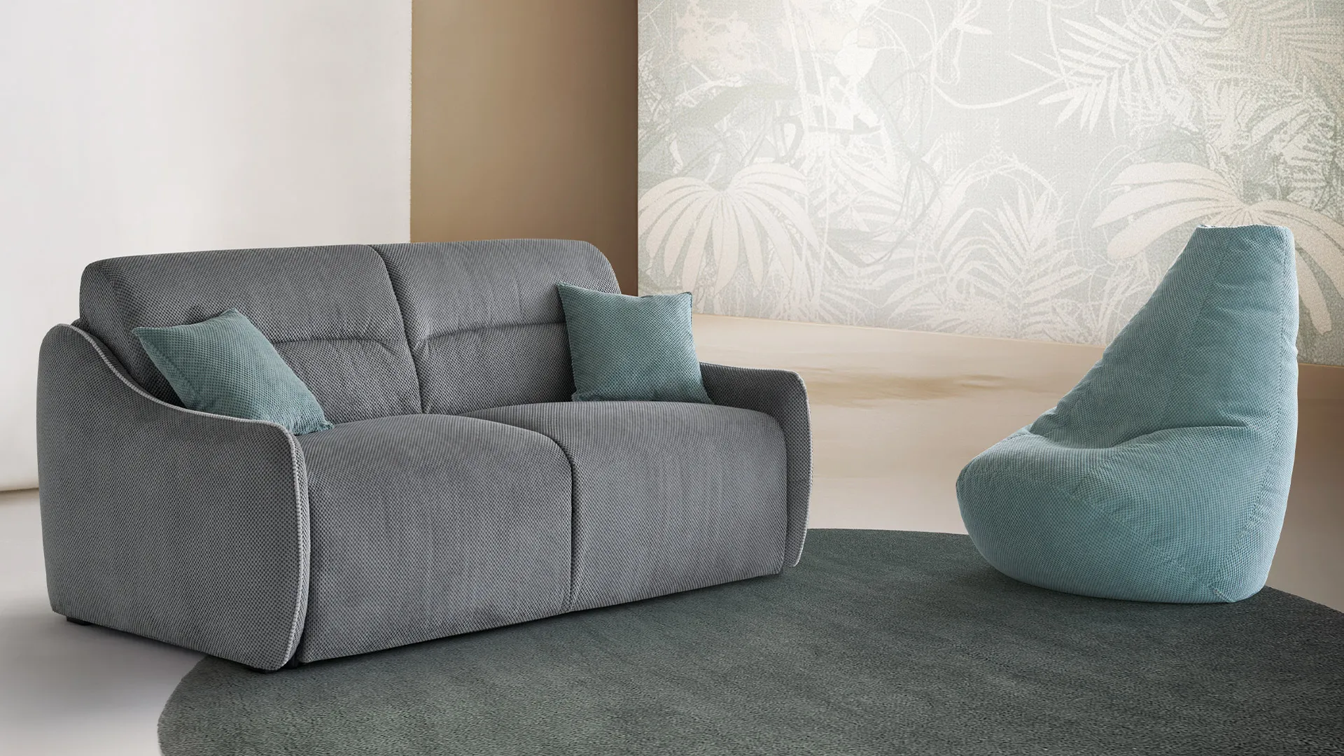 Divano letto Cherry Aerre Divani grigio con cuscini azzurri e poltrona a sacco Softbag su tappeto verde