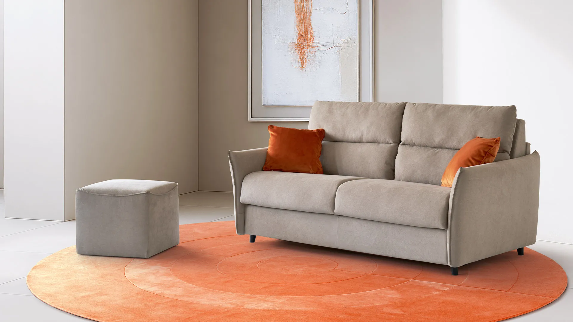 Divano letto Oasi Aerre Divani beige con cuscini arancio e pouf Cube su tappeto rotondo arancione