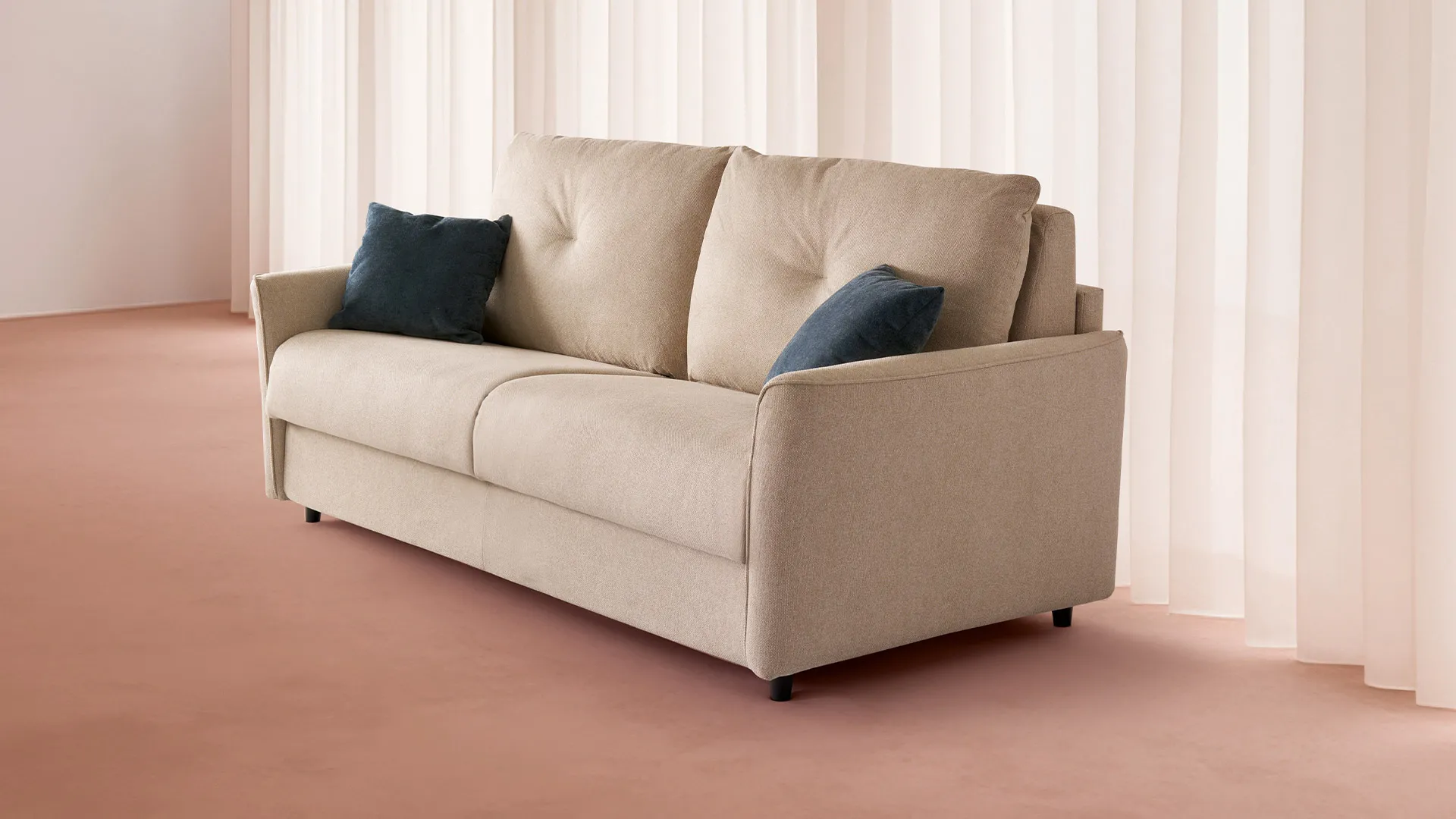 Divano letto Marion Aerre Divani avorio con cuscini blu, davanti a tende rosa