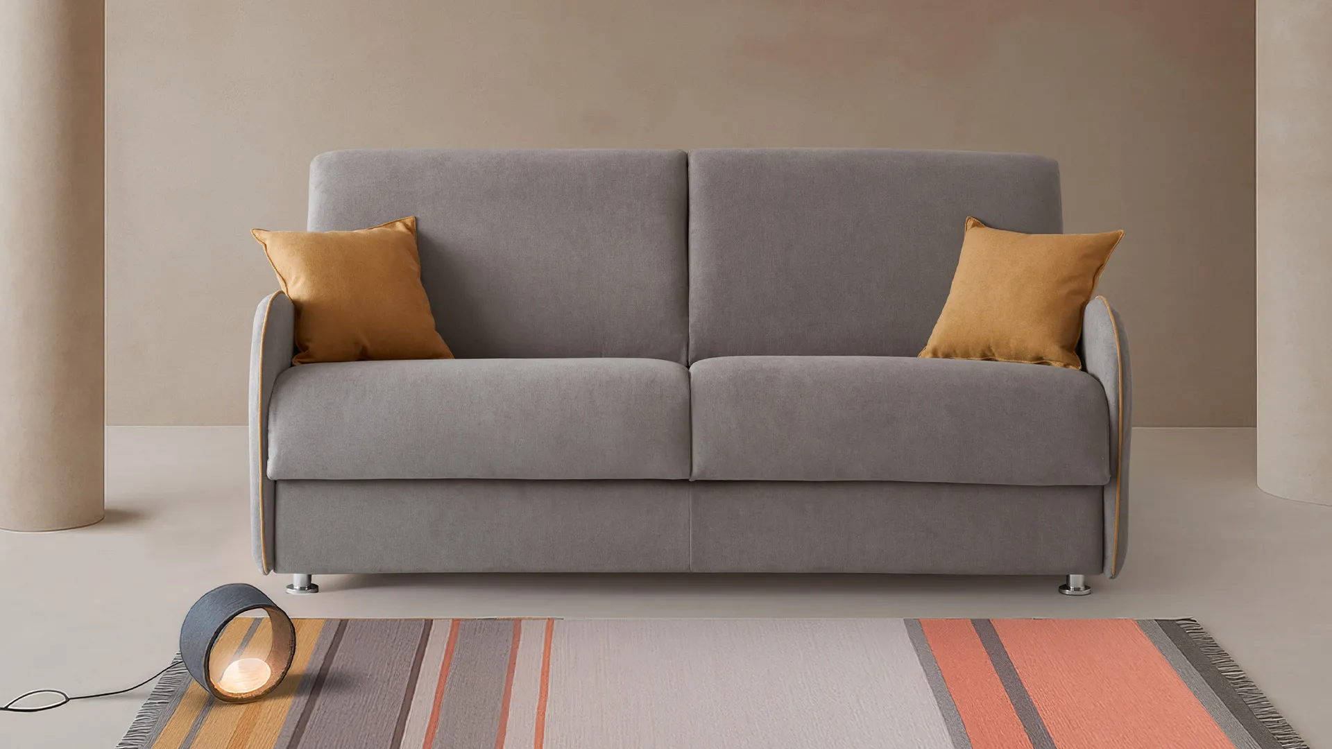 Divano letto Titti Basic Aerre Divani grigio con cuscini senape su tappeto a righe