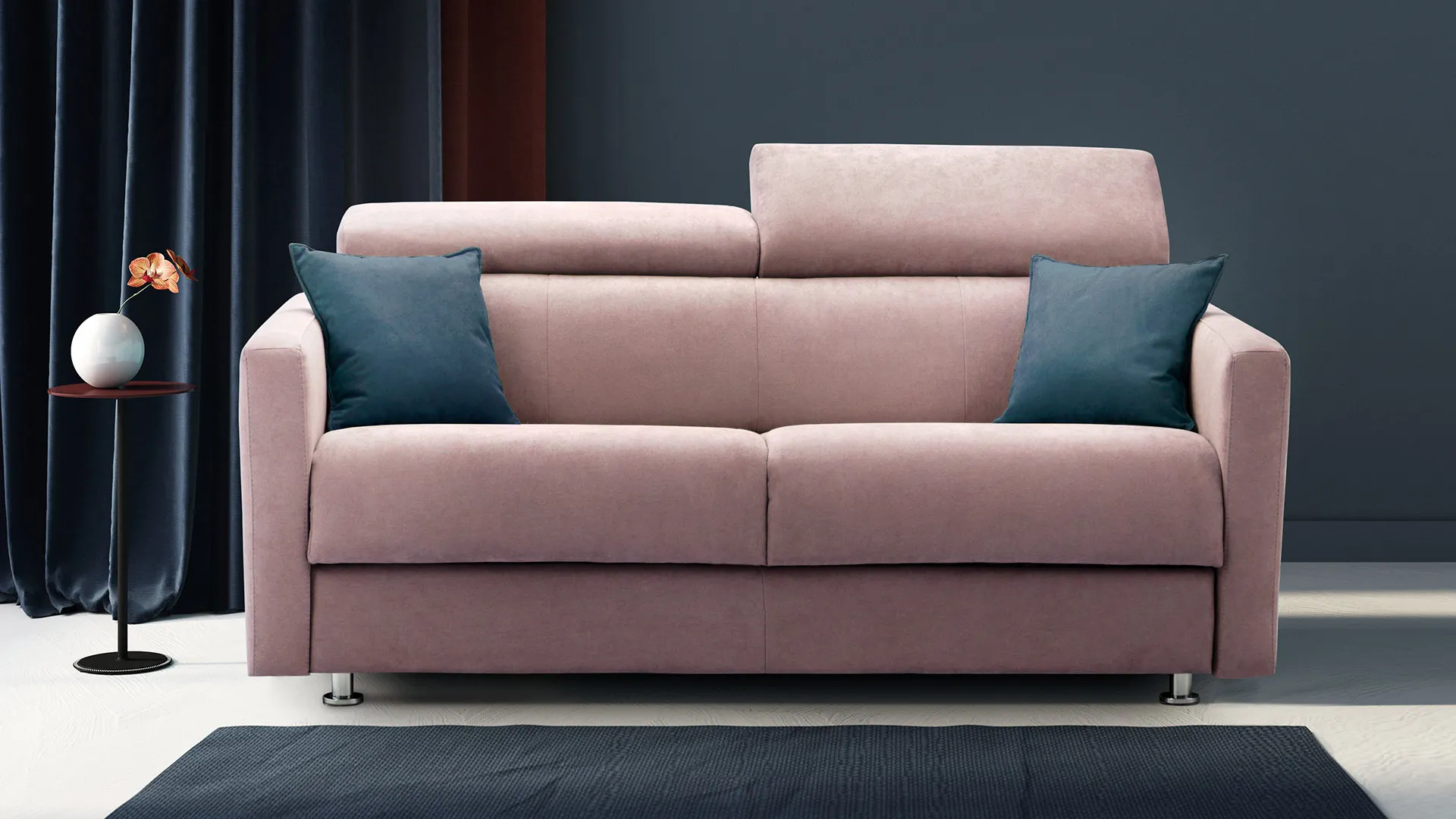 Divano letto Ingrid Aerre Divani rosa antico con cuscini blu davanti a una tenda scura