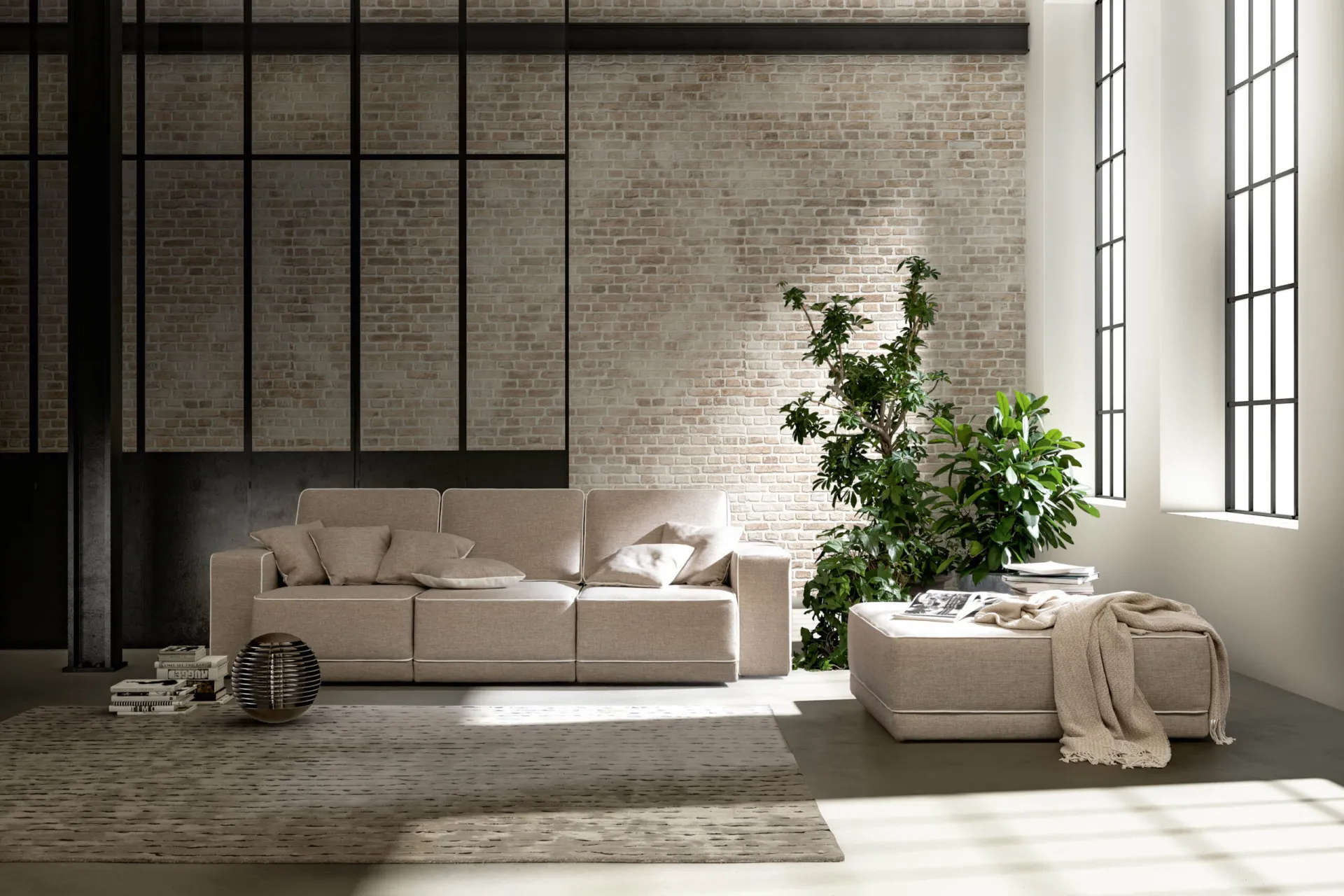 Divano Double Samoa beige con sedute estraibili e pouf, in un loft con pareti in mattoni chiari