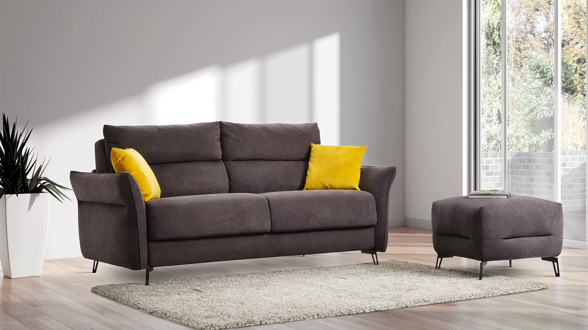 Divano letto Soave Aerre Divani grigio talpa con cuscini gialli e pouf in un soggiorno