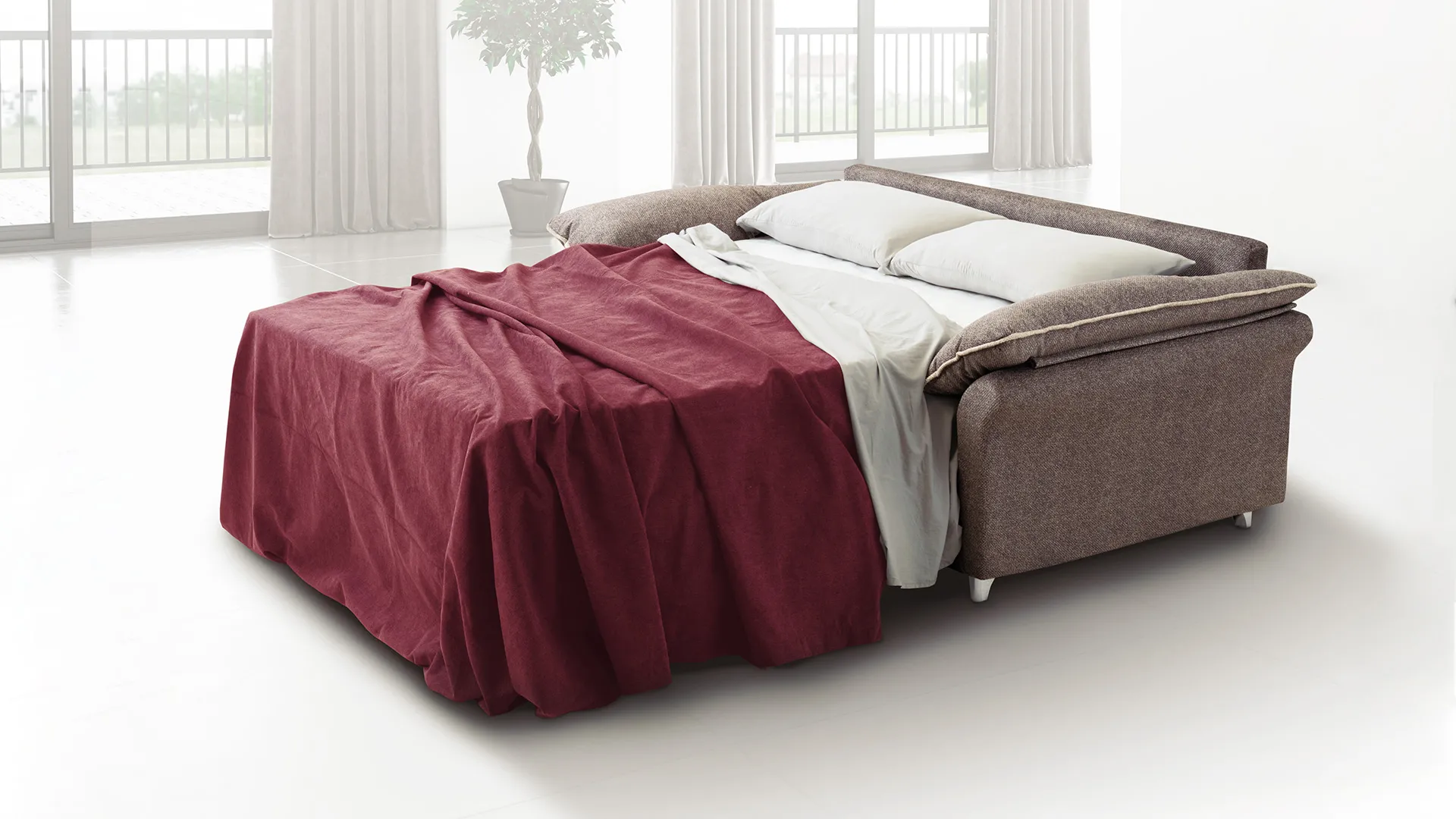 Divano letto Elvia Aerre Divani aperto con coperta bordeaux davanti a una vetrata