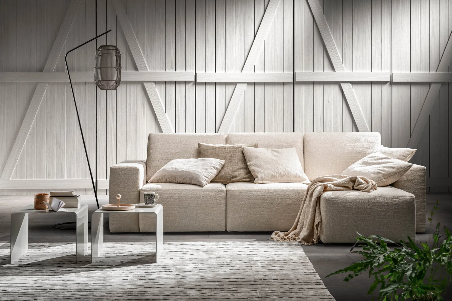 Divano Mono Samoa lineare beige con plaid, davanti a un portone bianco