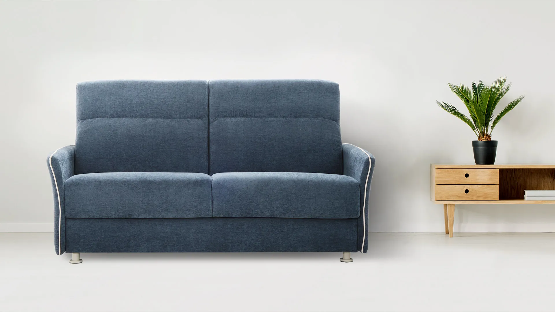 Divano letto Zara Special Aerre Divani blu con bordino chiaro accanto a un mobile in legno