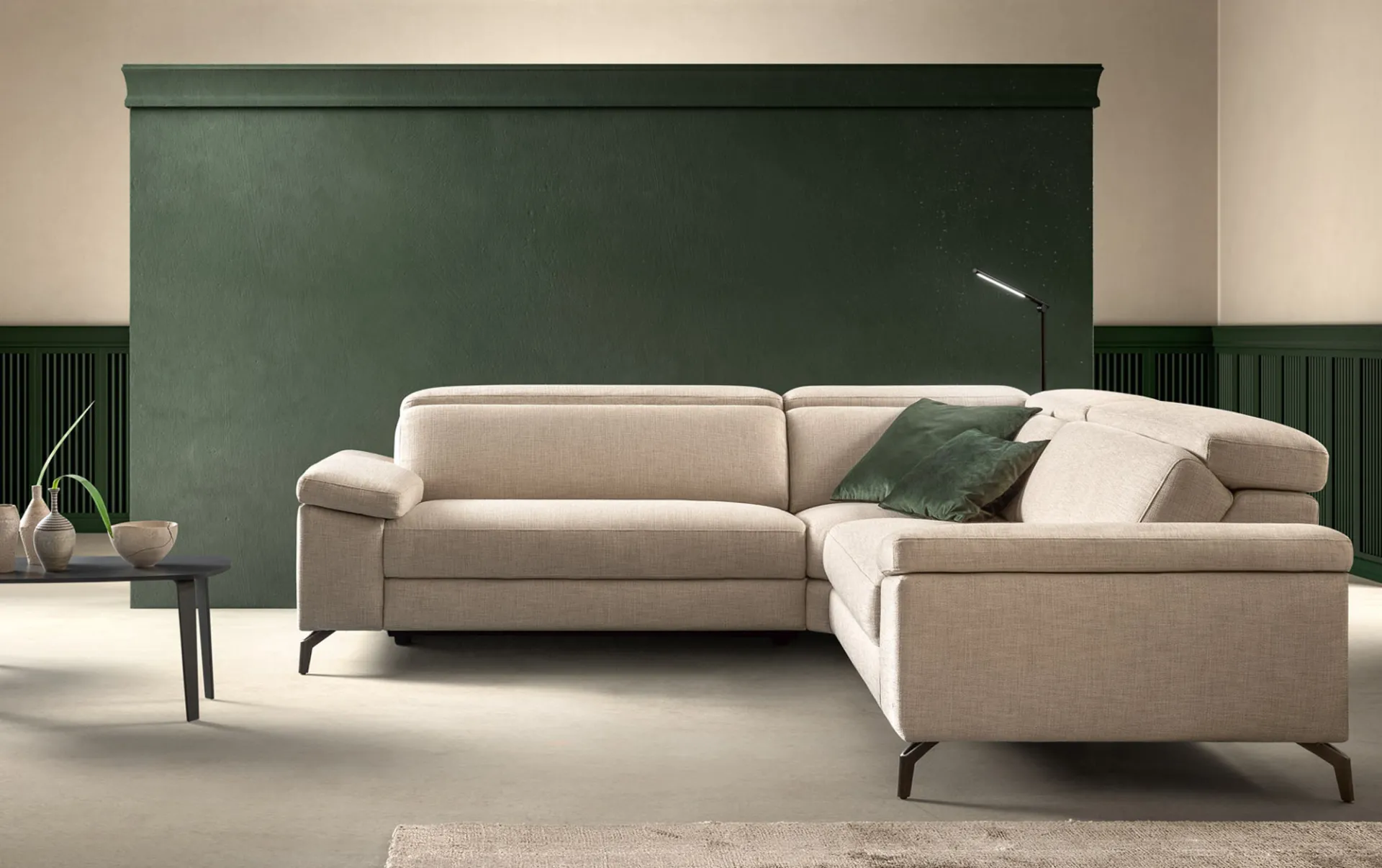 Divano relax Space Action Samoa beige in composizione angolare, davanti a una parete verde