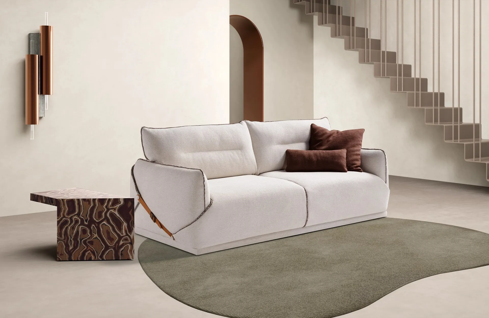 Divano letto Noah Dienne bianco panna con cuscini marroni in un ambiente con scala e tappeto verde