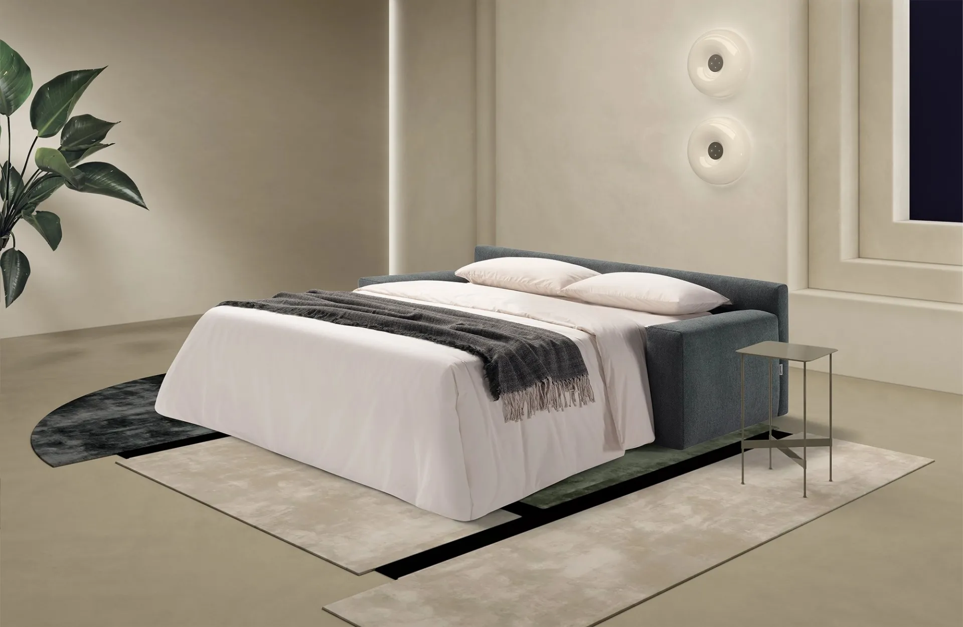 Divano letto Loop Dienne aperto con letto rifatto su tappeti sovrapposti