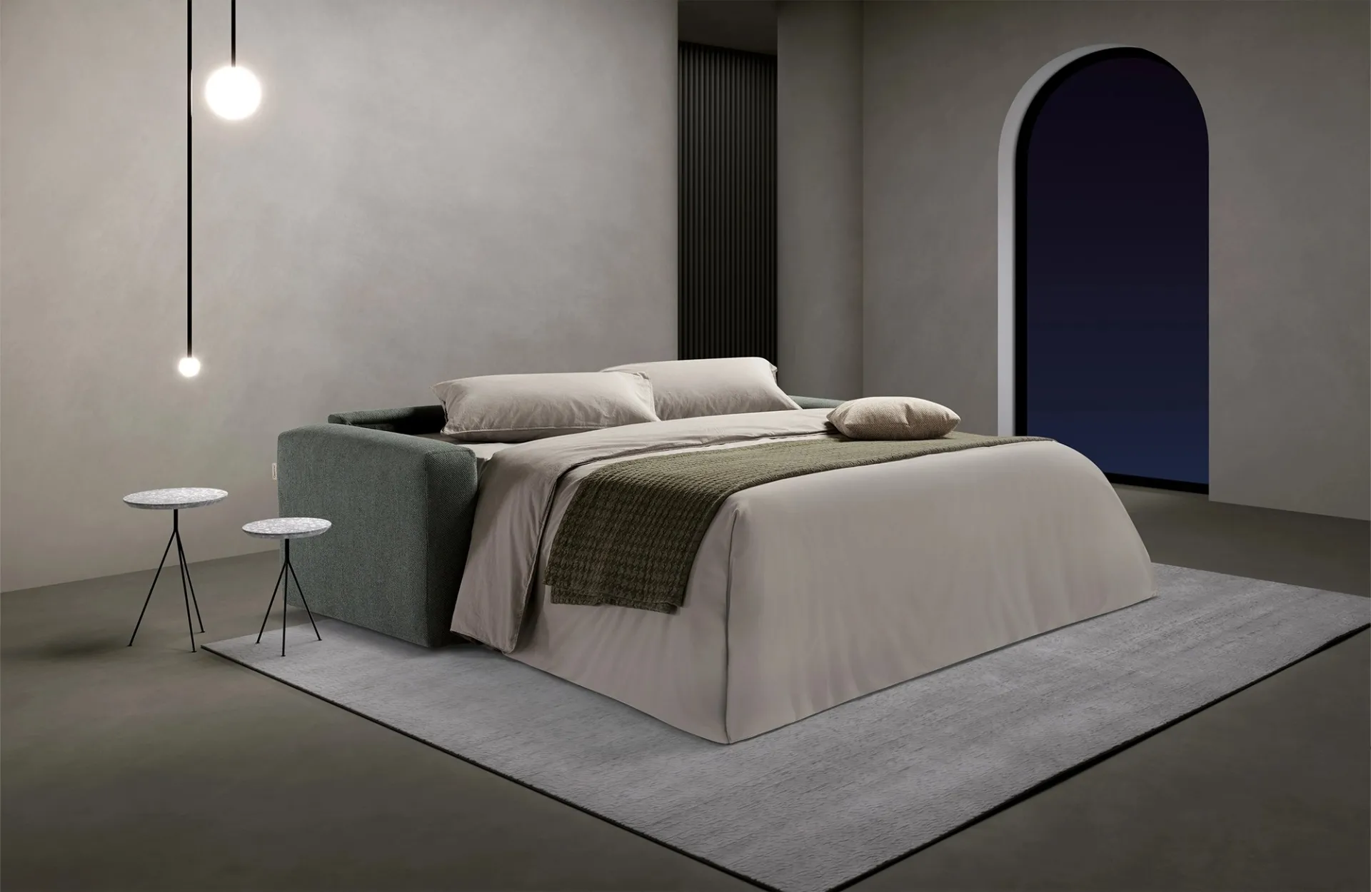 Divano letto Square Dienne aperto di sera sotto una lampada a sospensione