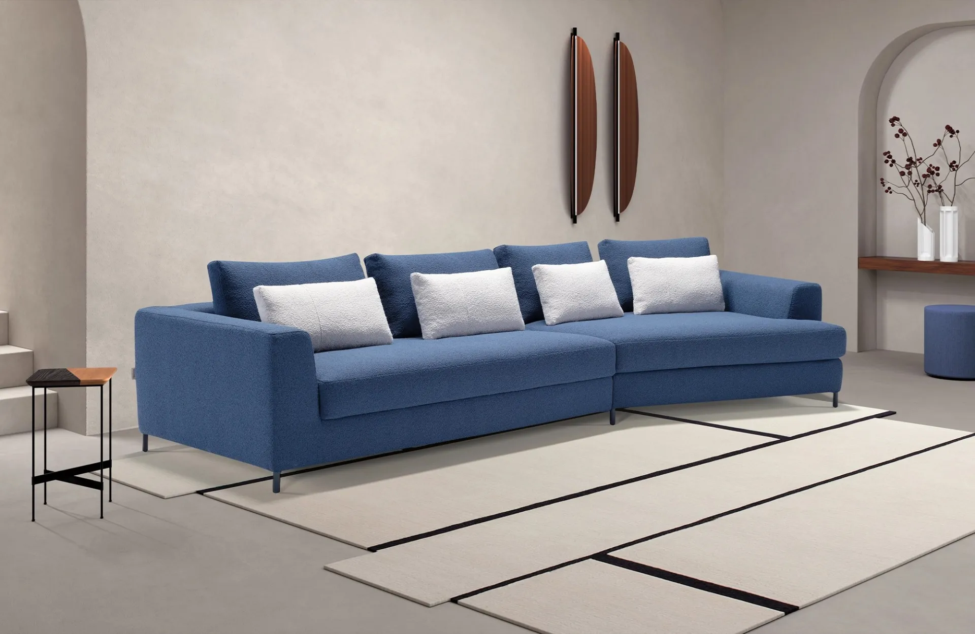 Divano letto Loy Dienne blu con cuscini grigio chiaro e terminale ad angolo su tappeto a righe