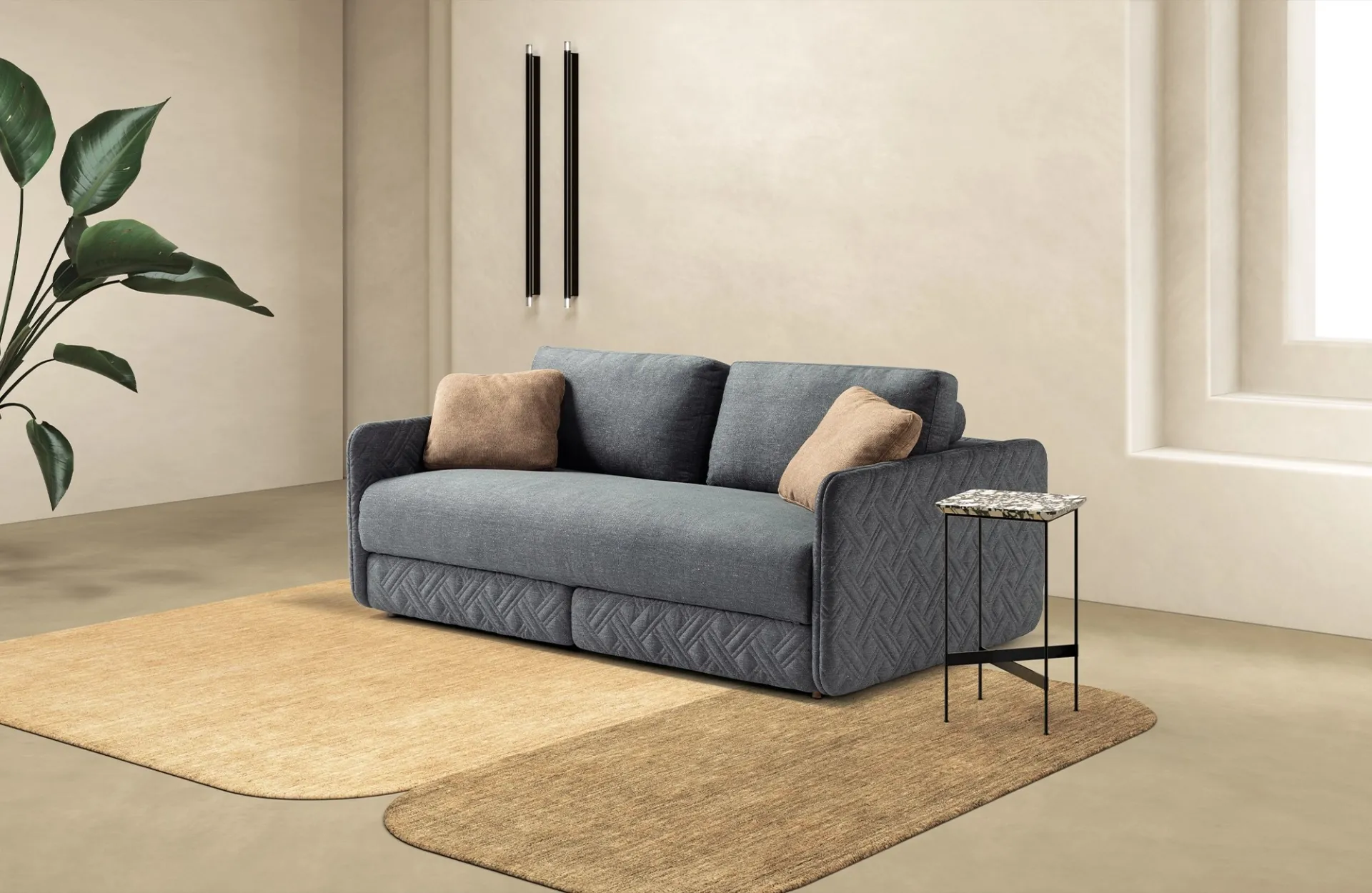 Divano letto Lia Dienne grigio con scocca trapuntata e cuscini color sabbia su tappeti ocra