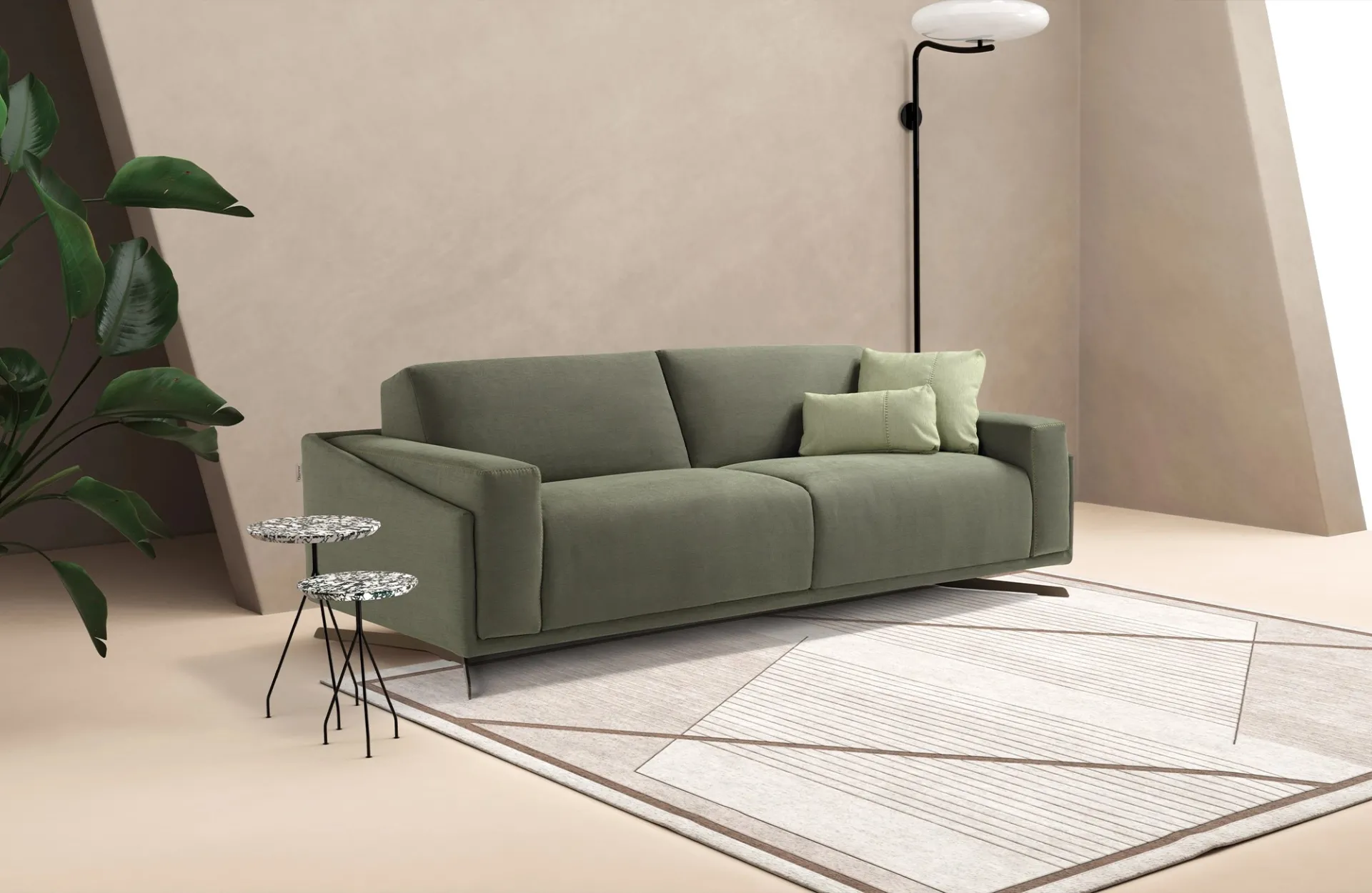 Divano letto Space Dienne verde salvia con piedi color ottone accanto a tavolini in terrazzo