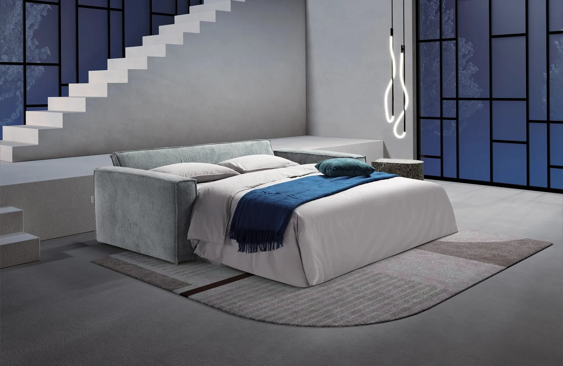 Divano letto More Dienne aperto di notte con coperta blu