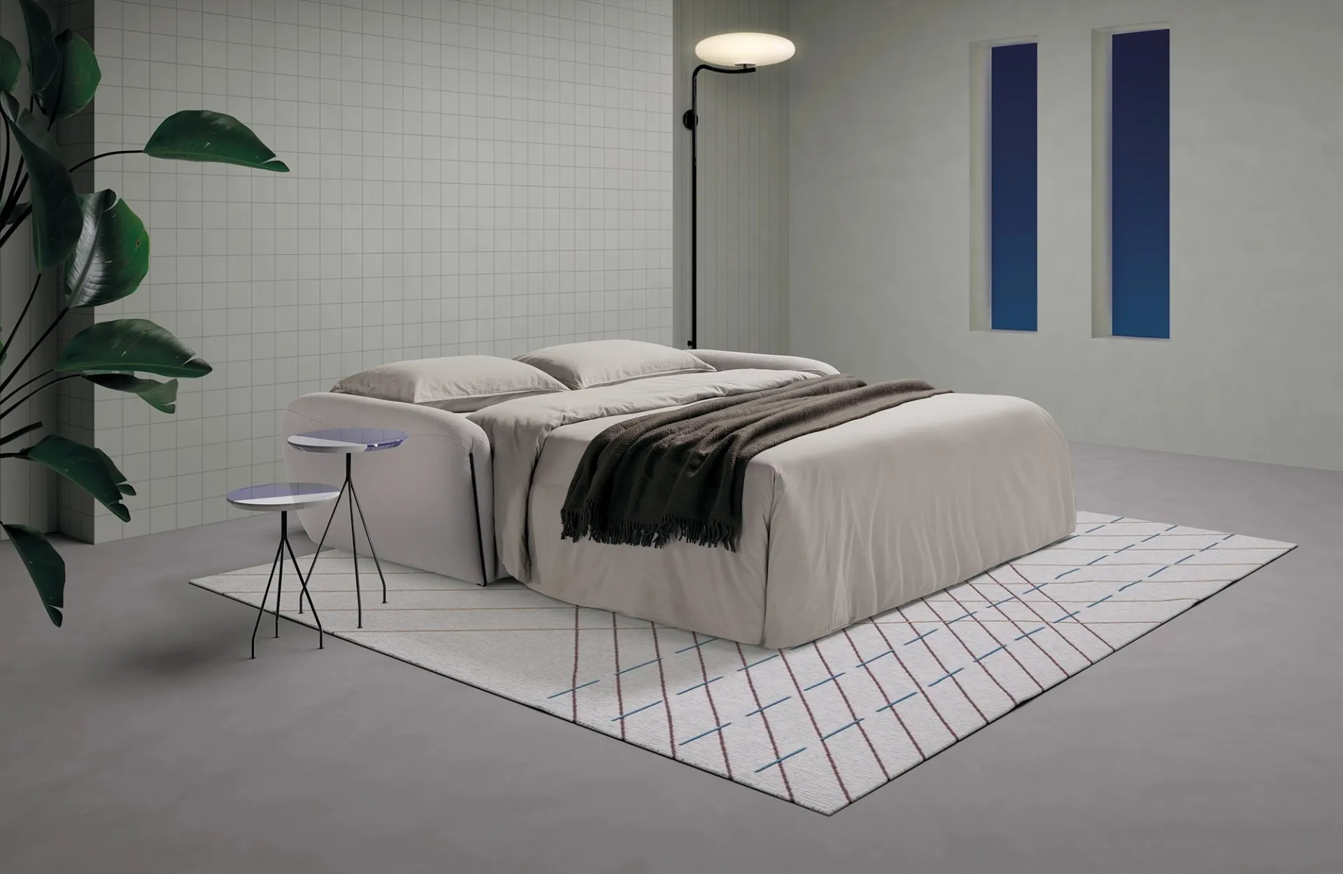 Divano letto Soul Dienne aperto con coperta scura su tappeto a rombi
