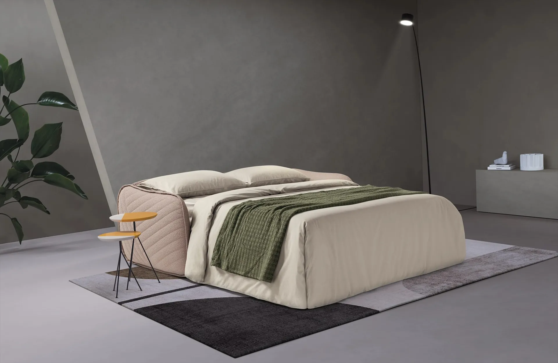 Divano letto Moon Dienne aperto con plaid verde su un tappeto chiaro