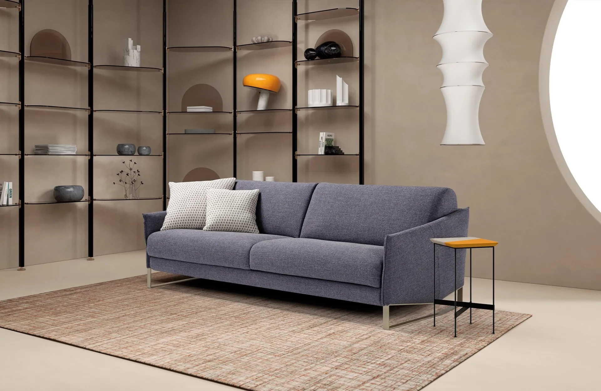 Divano letto Nice Dienne blu grigio davanti a una libreria a giorno, con tavolino arancione