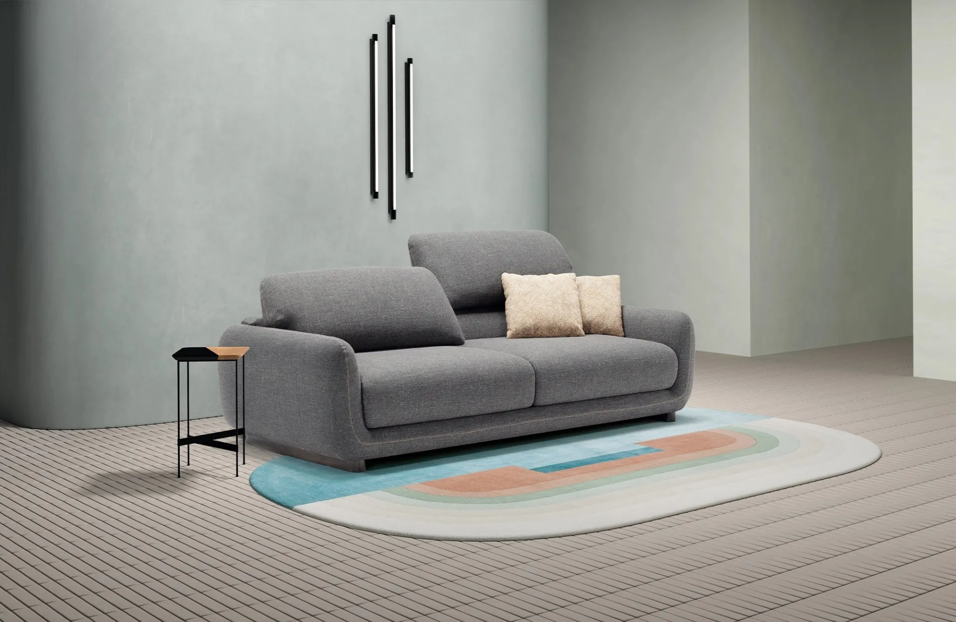 Divano letto Bob Dienne grigio antracite con uno schienale alzato, su tappeto ovale colorato