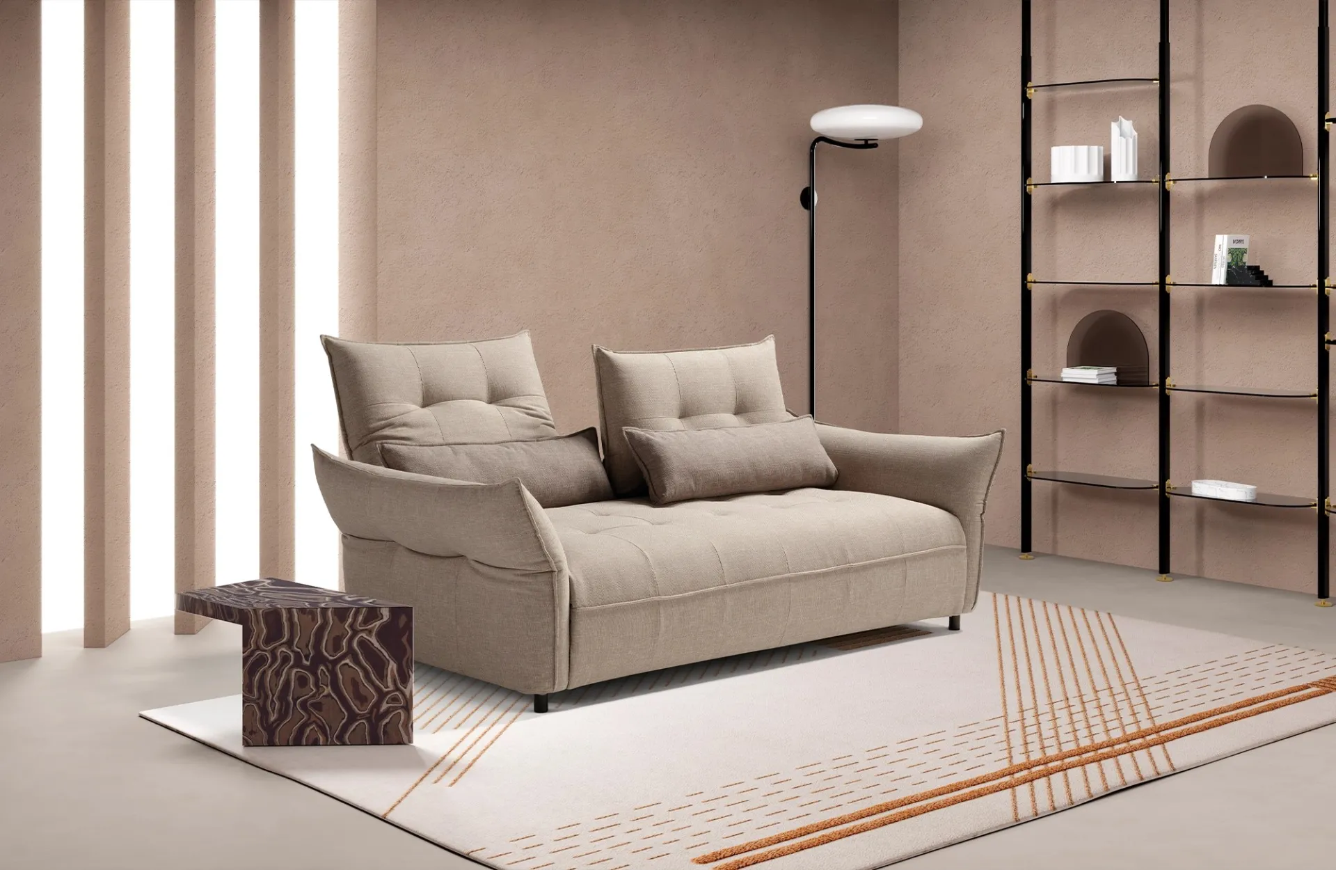 Divano letto Bill Dienne beige con braccioli ad ala inclinati, accanto a una libreria in metallo