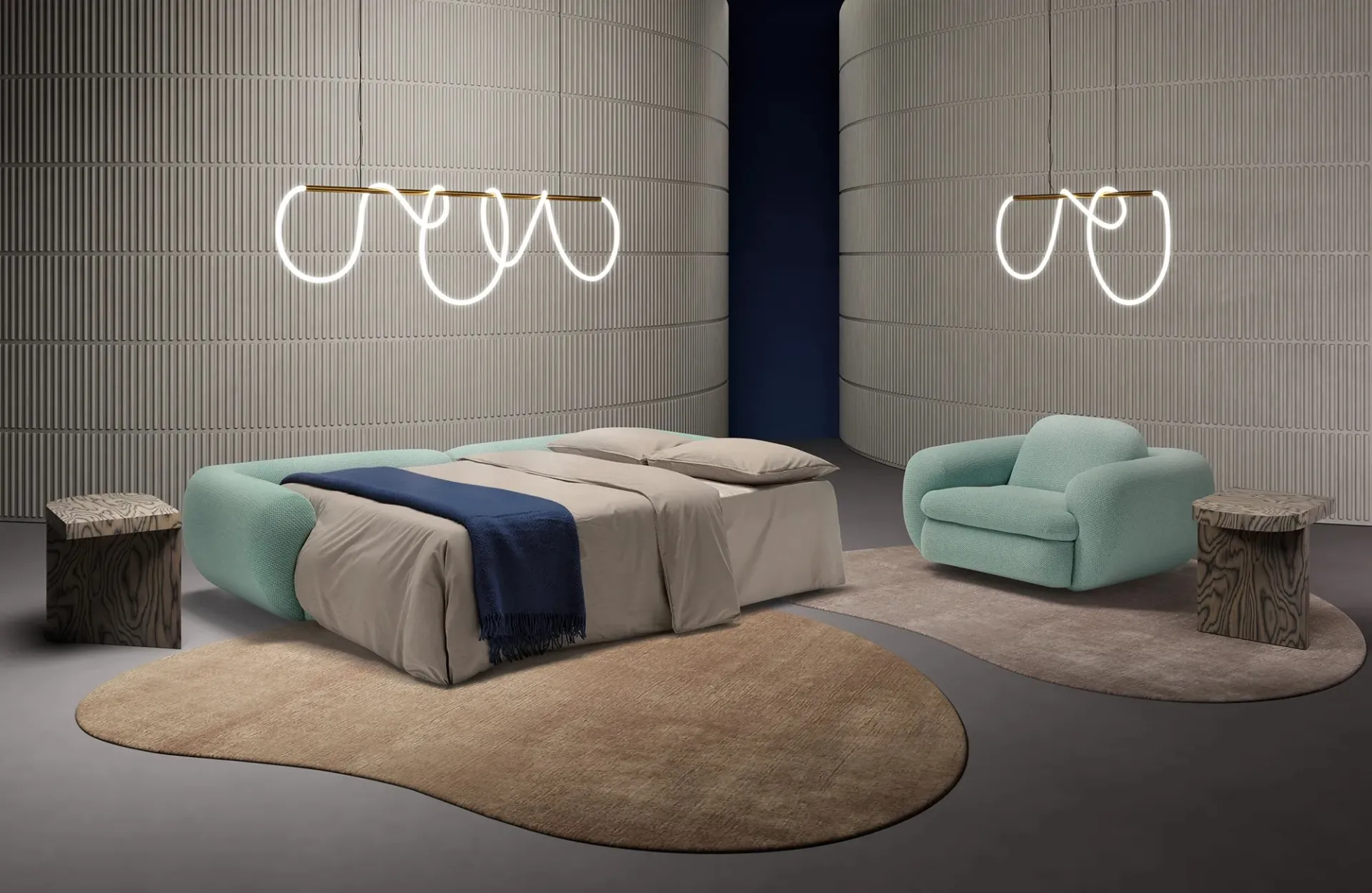 Divano letto Curvi Dienne aperto in senso trasversale con plaid blu, accanto alla poltrona