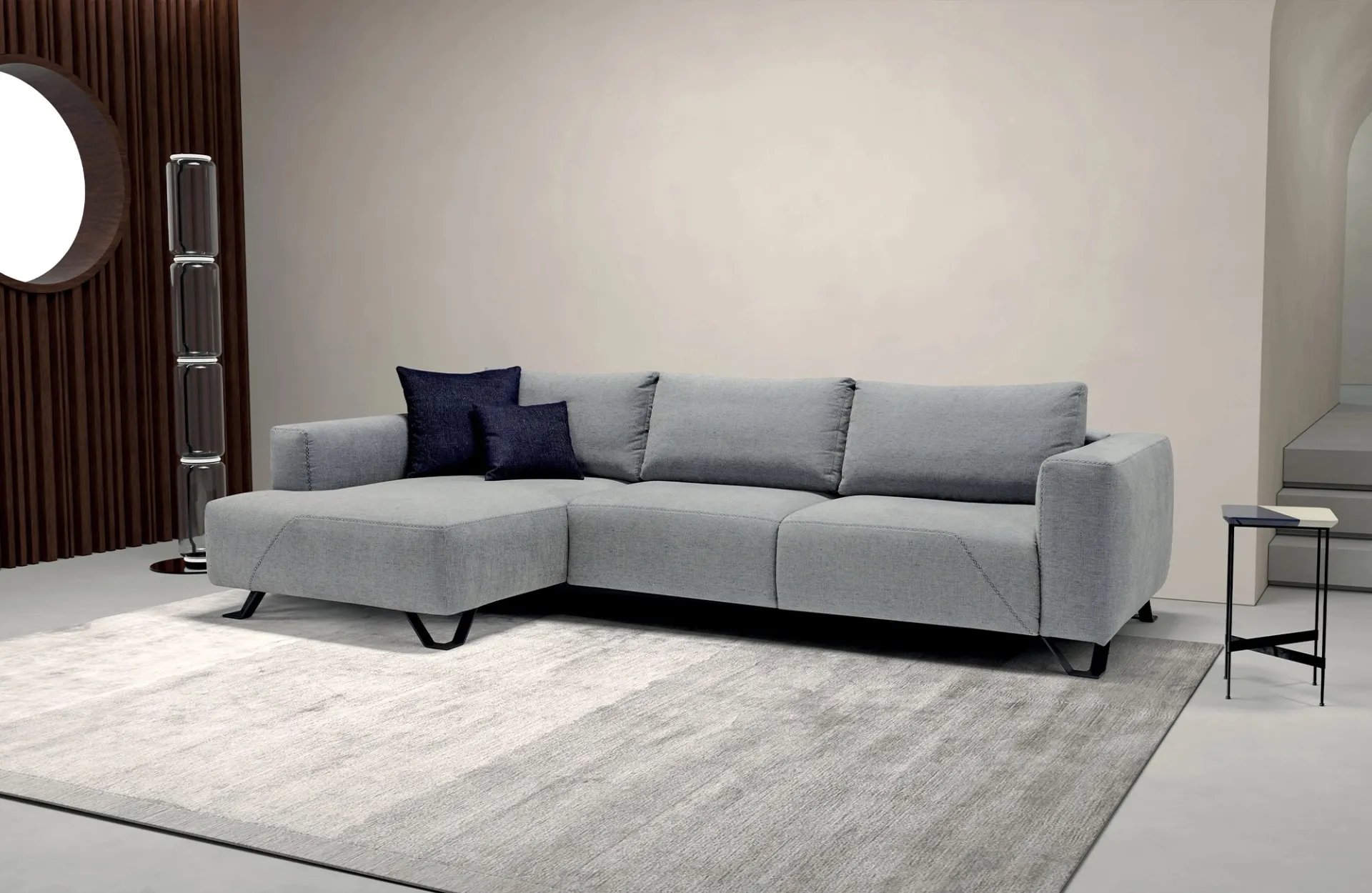 Divano letto Simple Dienne grigio chiaro con chaise longue e cuscini blu, su un grande tappeto