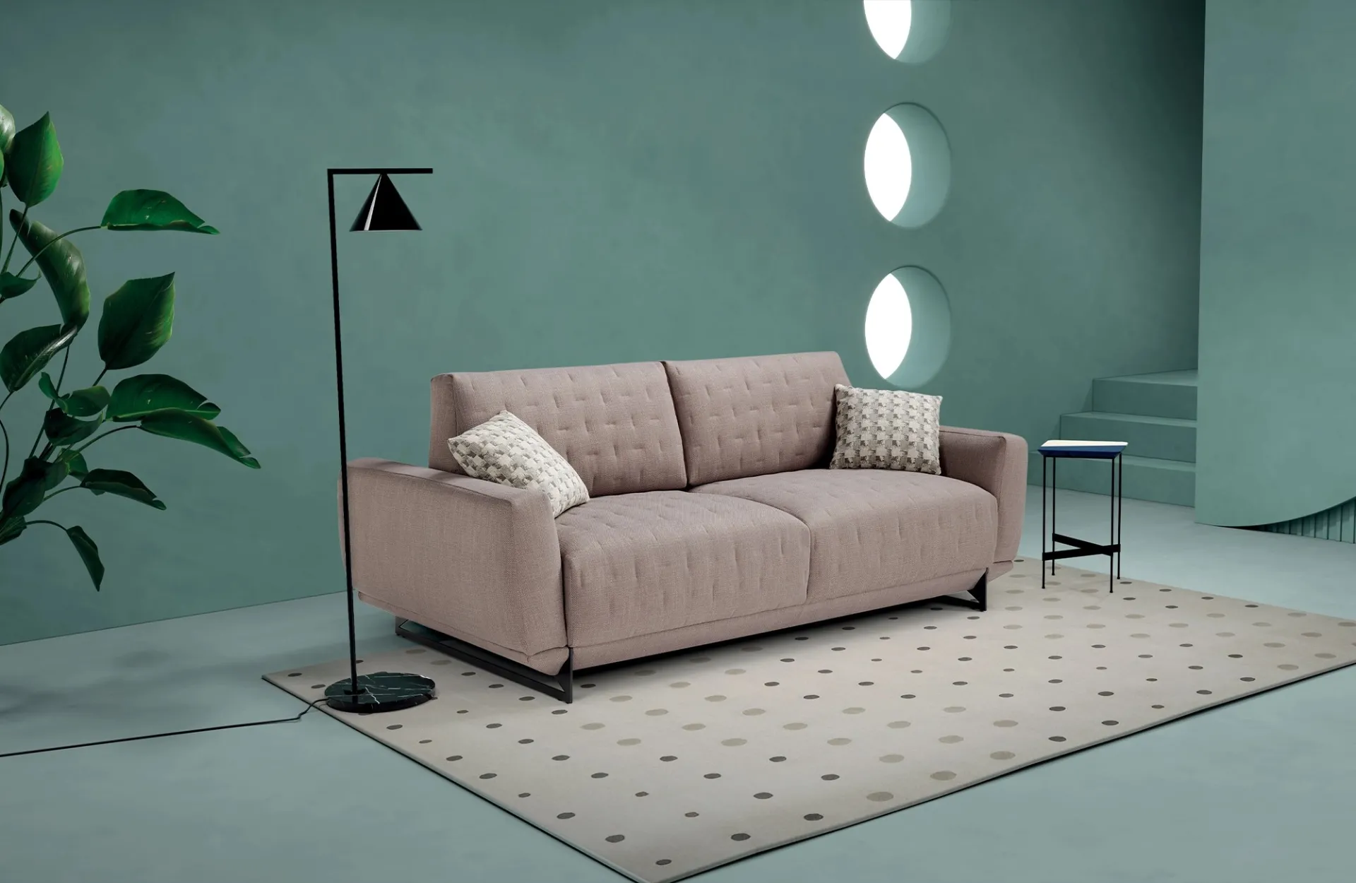 Divano letto Skin Dienne rosa cipria trapuntato su tappeto a pois, in una stanza verde acqua