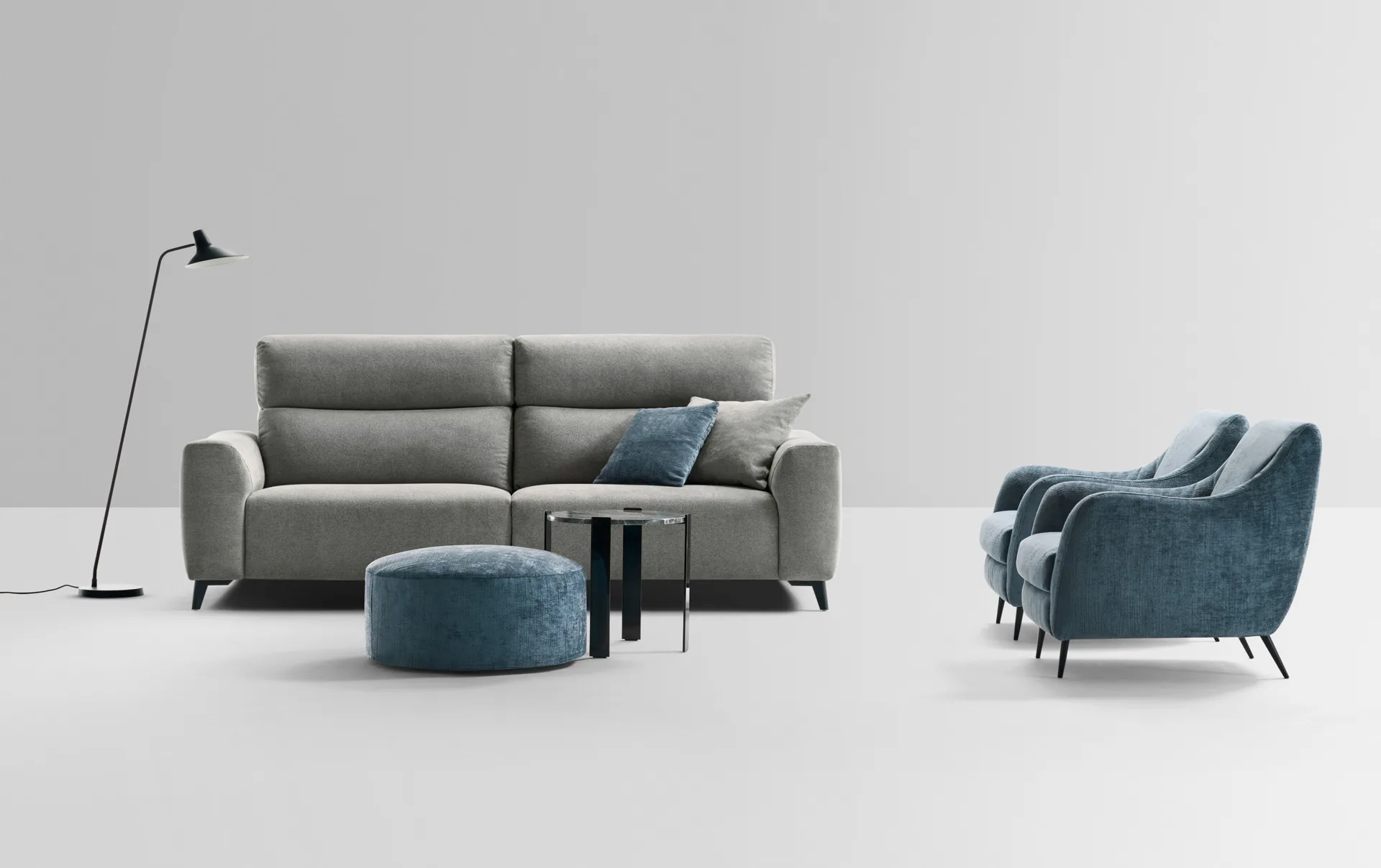 Divano Cordoba Rosini grigio con pouf blu e poltrona su fondo chiaro