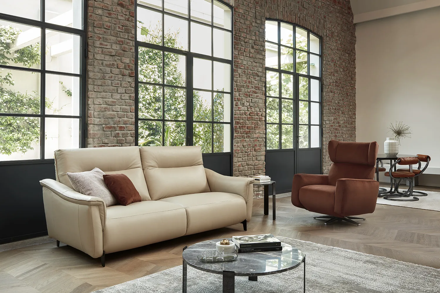 Divano Madrid Rosini in pelle crema con poltrona rossa in un loft