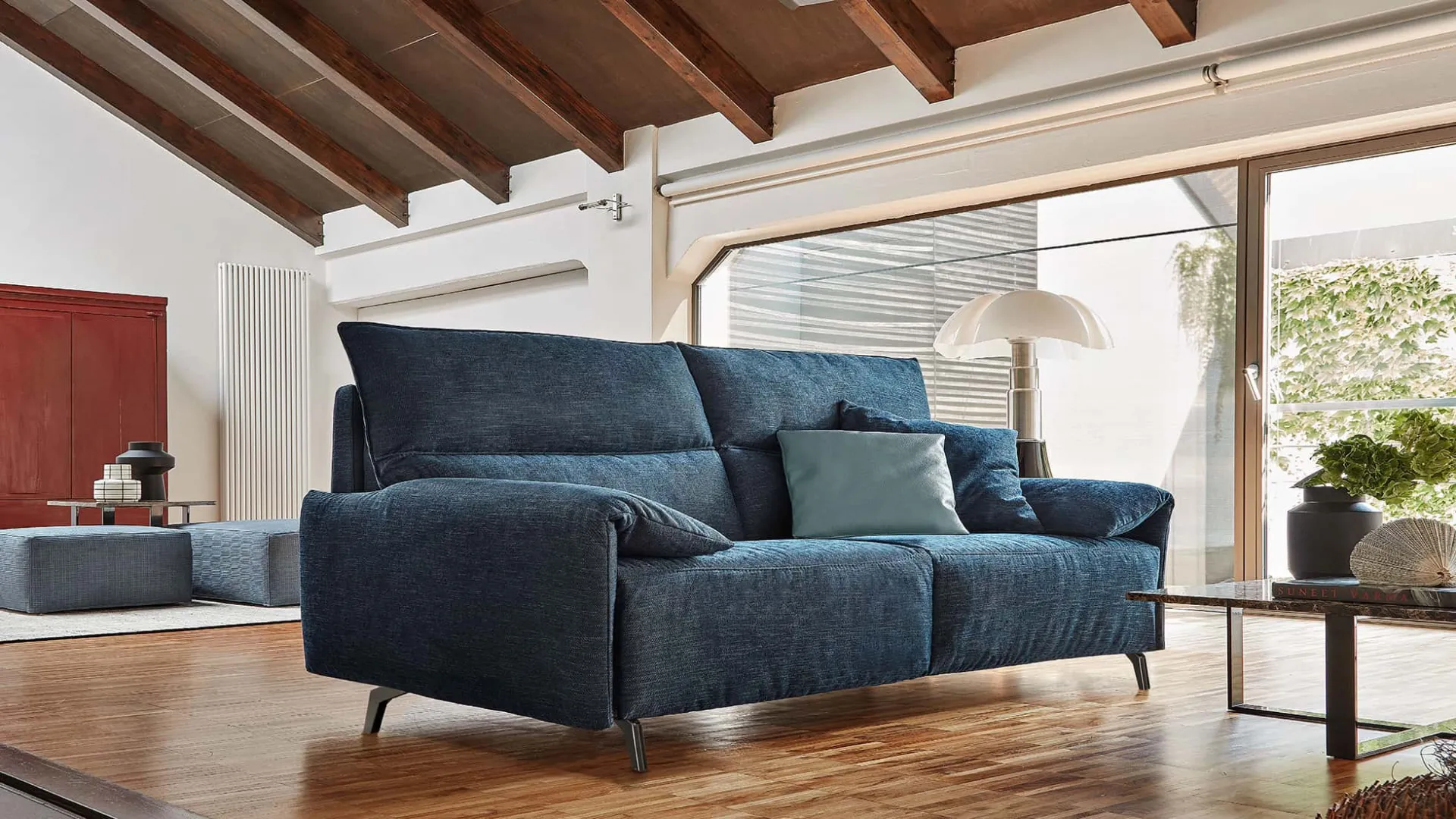 Divano letto Stelvio Rosini blu in una mansarda con travi in legno
