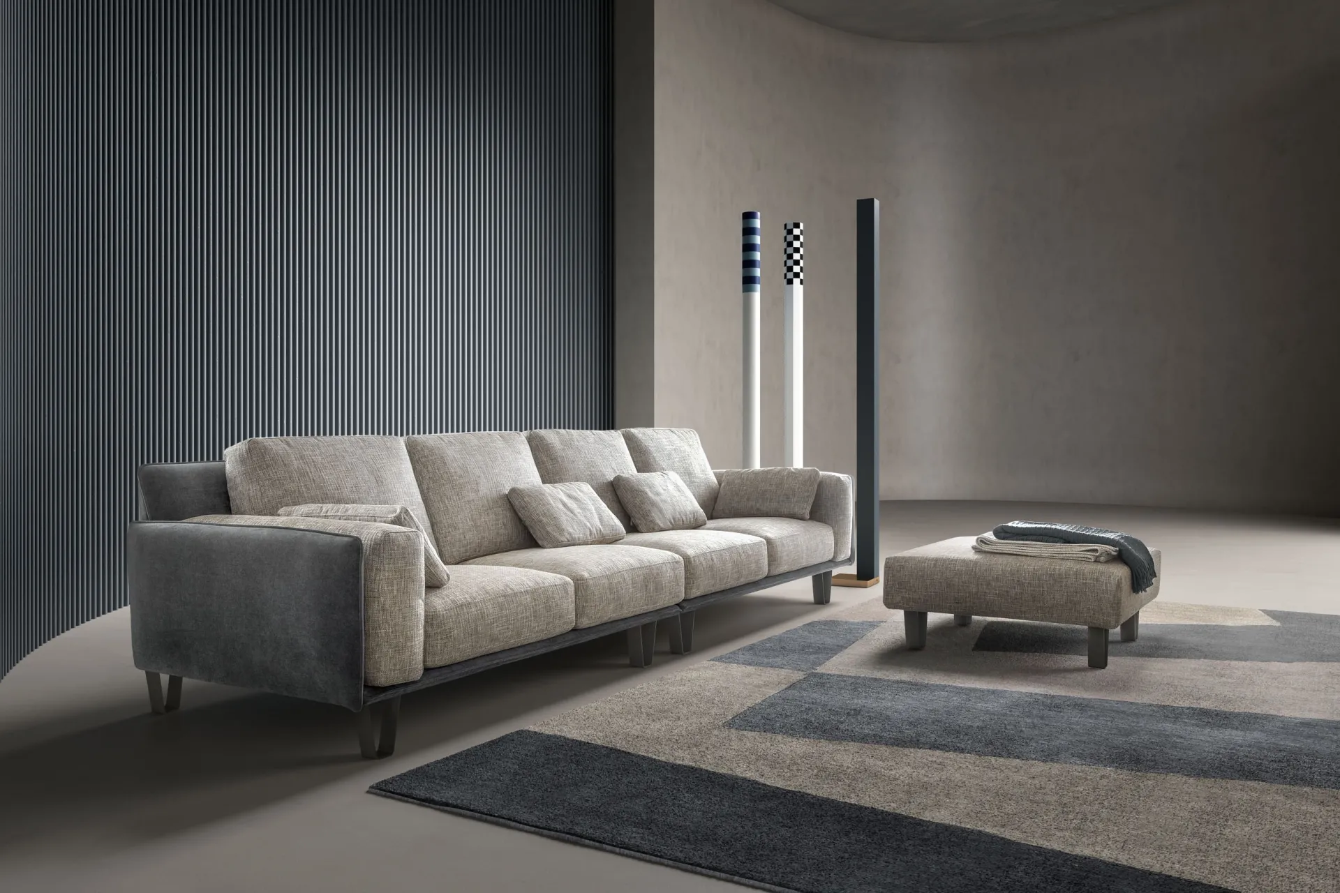 Divano Living Samoa lineare con braccioli grigi a contrasto e pouf, su un tappeto geometrico