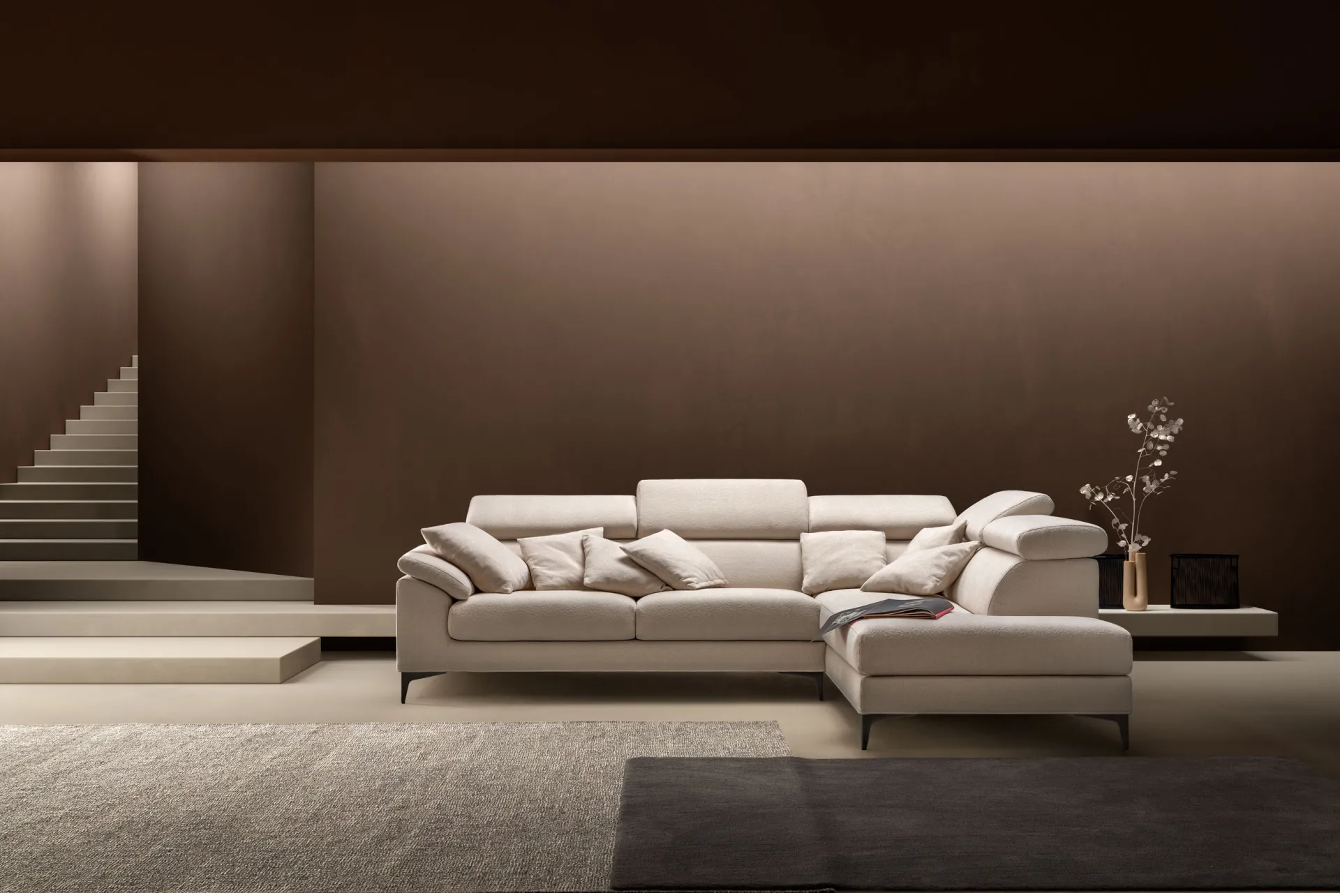 Divano componibile Loft Samoa color panna ad angolo con poggiatesta alzati, in un ambiente marrone