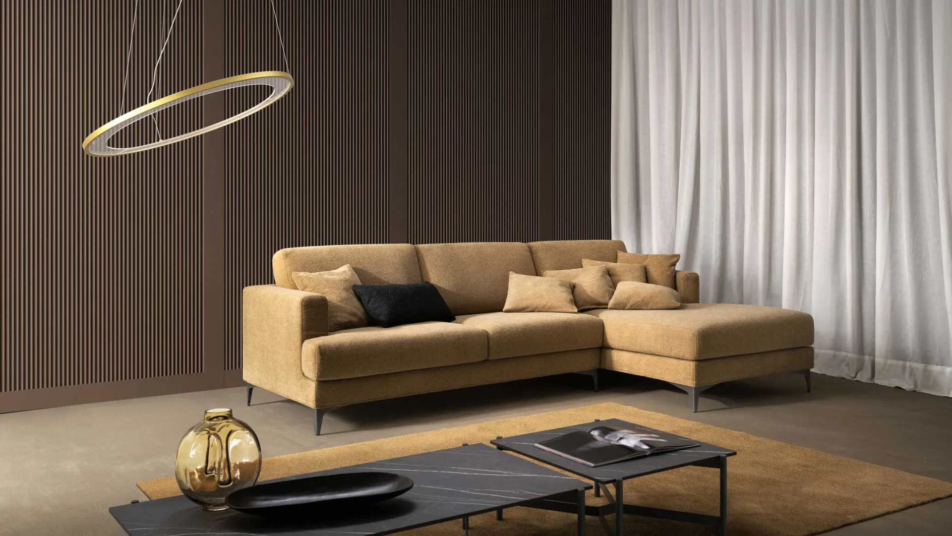 Divano componibile Cherry Samoa ocra con chaise longue, accanto a una lampada ad anello