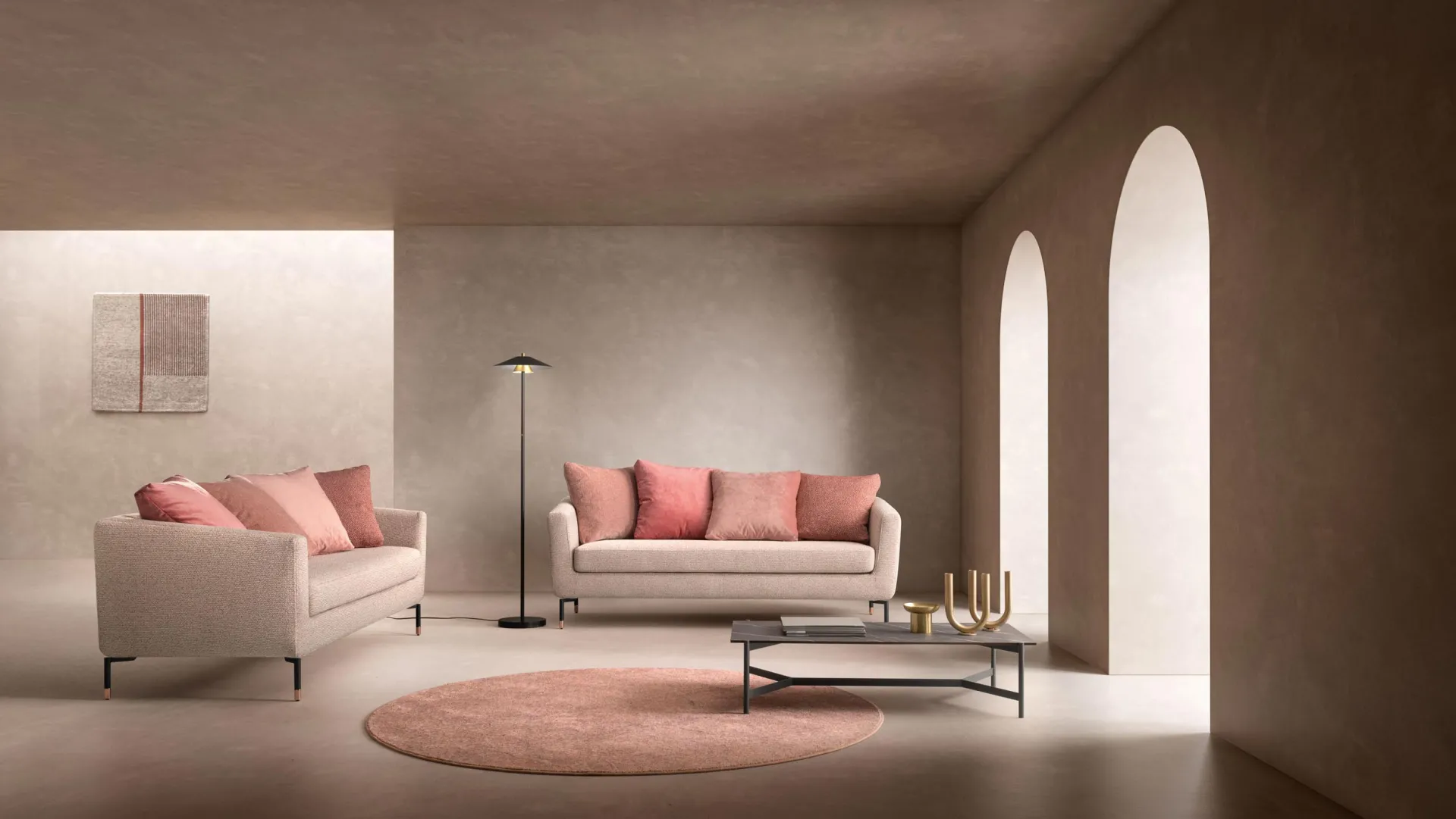 Due divani Crisp Samoa chiari con cuscini rosa, in un ambiente con archi e tappeto tondo
