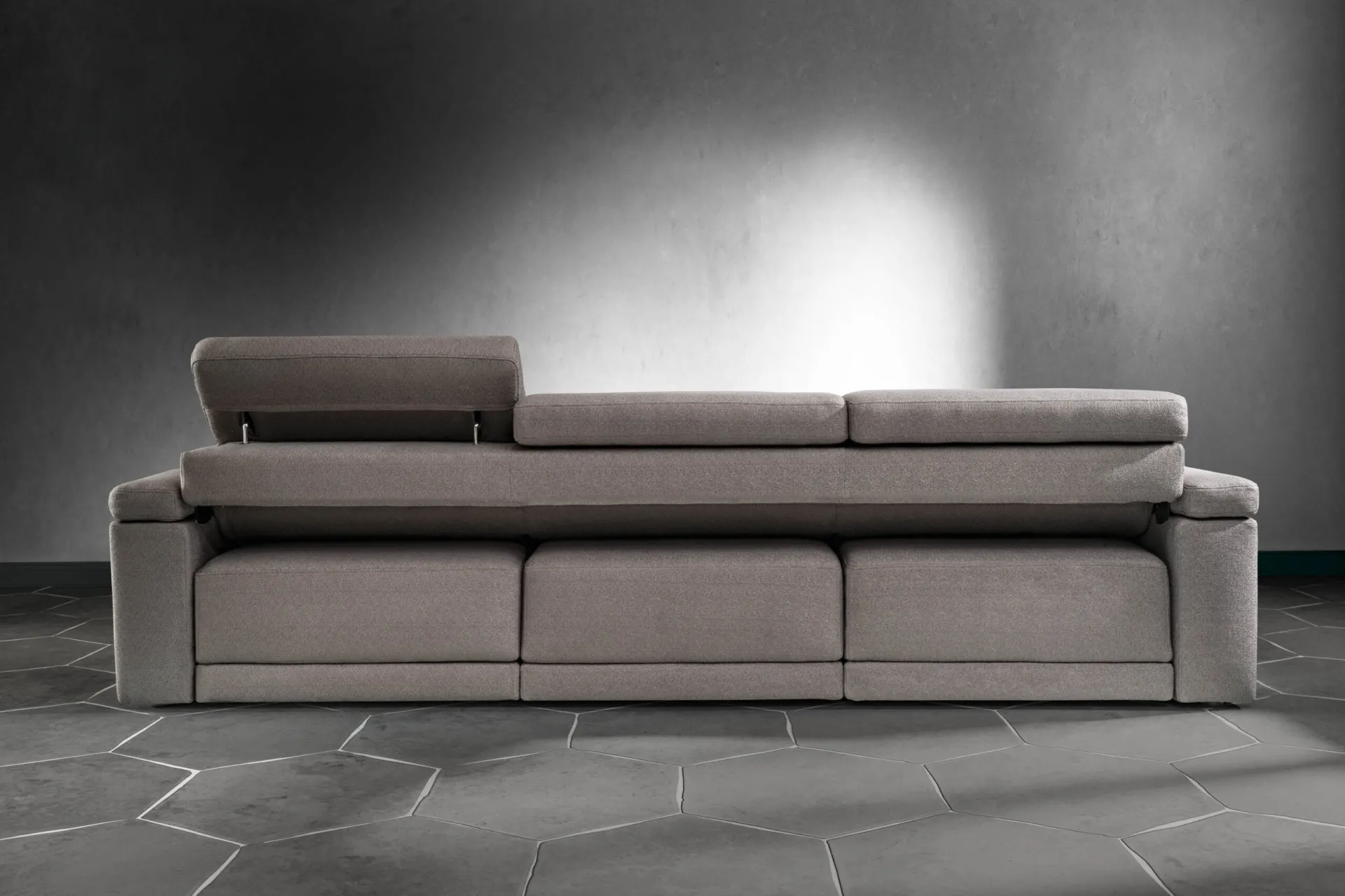 Divano Comfort Samoa grigio a tre posti con un poggiatesta alzato, su pavimento esagonale