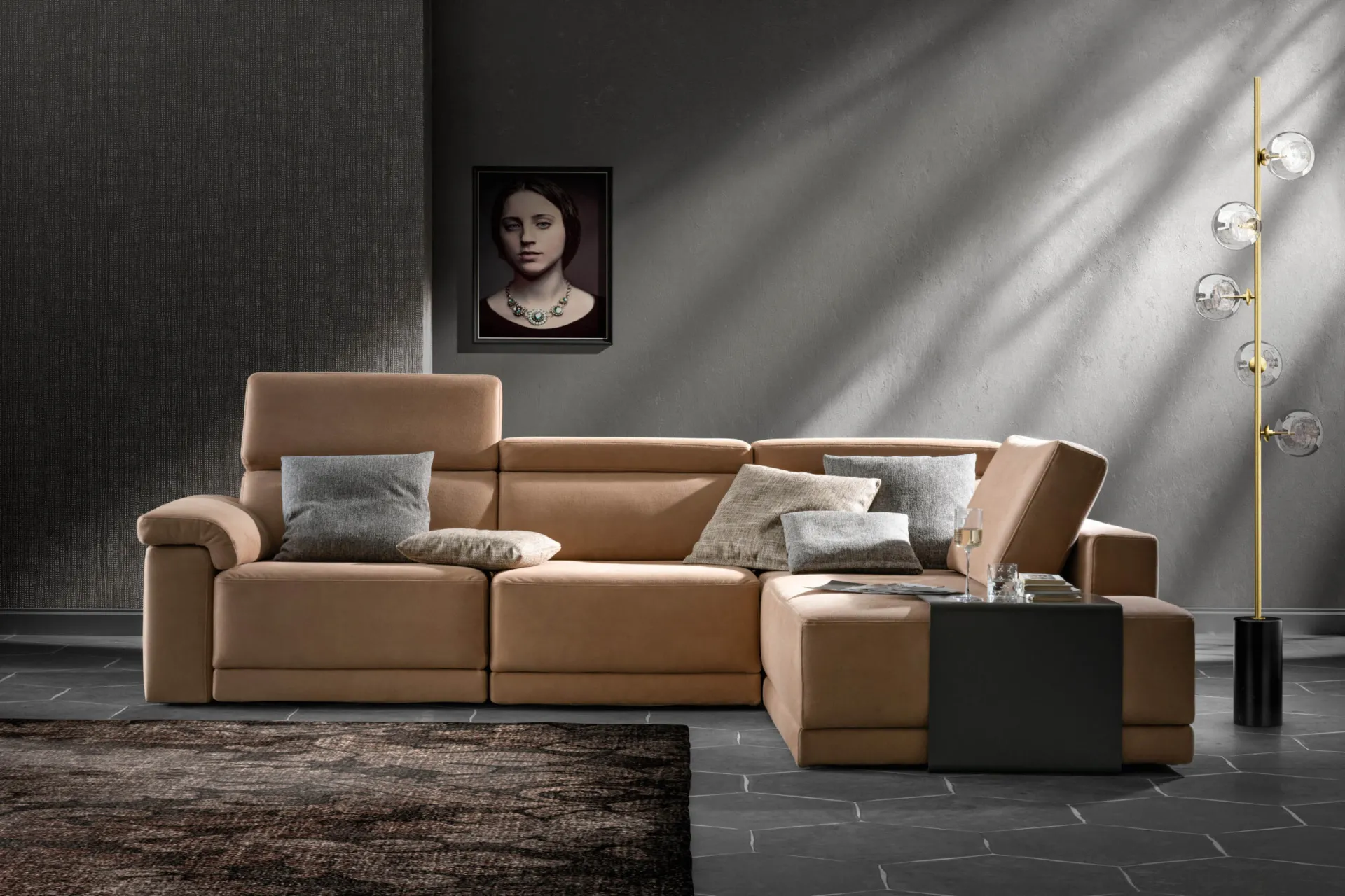 Divano angolare Comfort Samoa color cuoio con cuscini grigi, accanto a una lampada da terra
