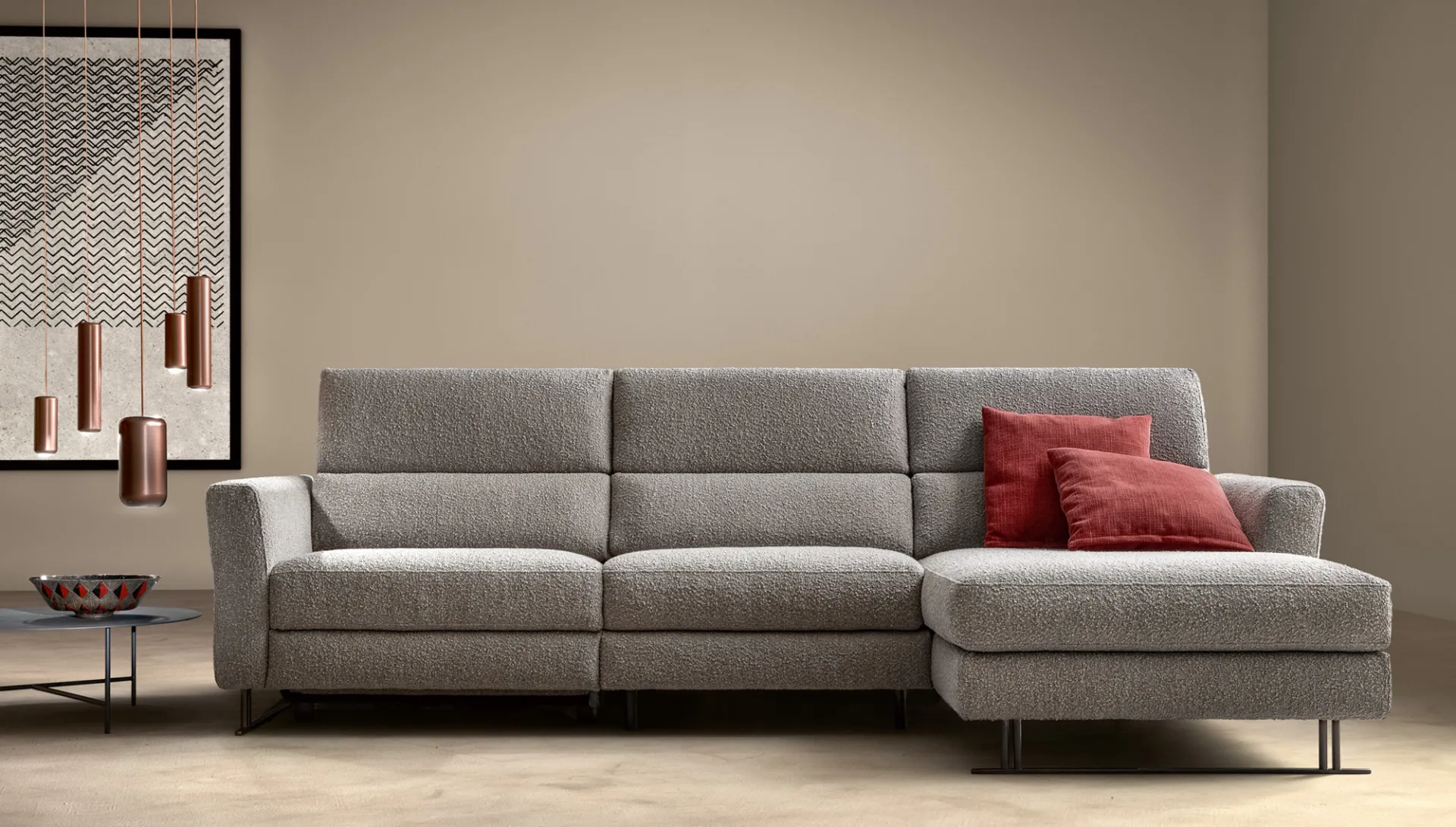 Divano relax Space Spark Samoa grigio con chaise longue e cuscini rossi, sotto lampade in rame