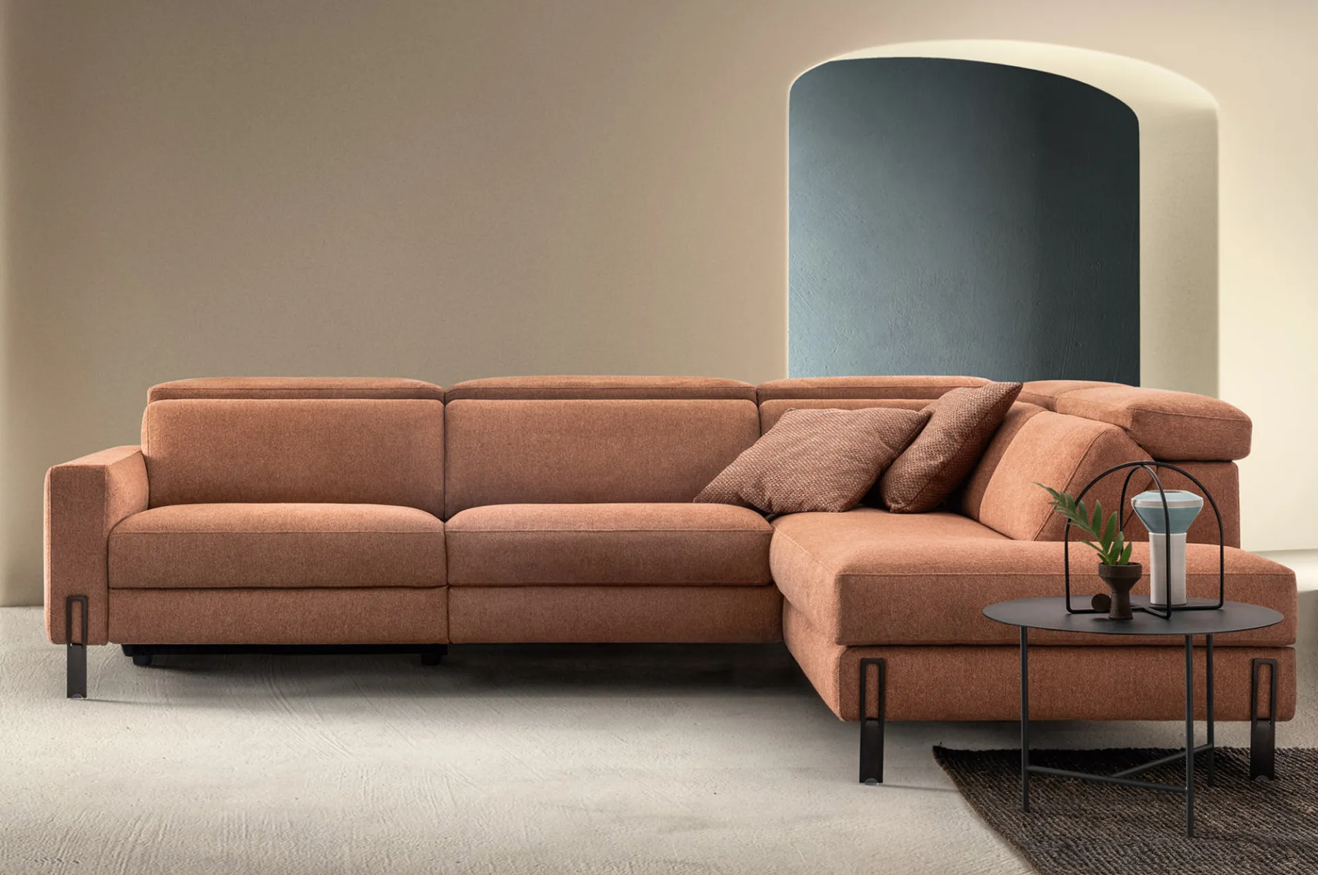 Divano relax Space Speed Samoa terracotta ad angolo con poggiatesta, davanti a un arco blu