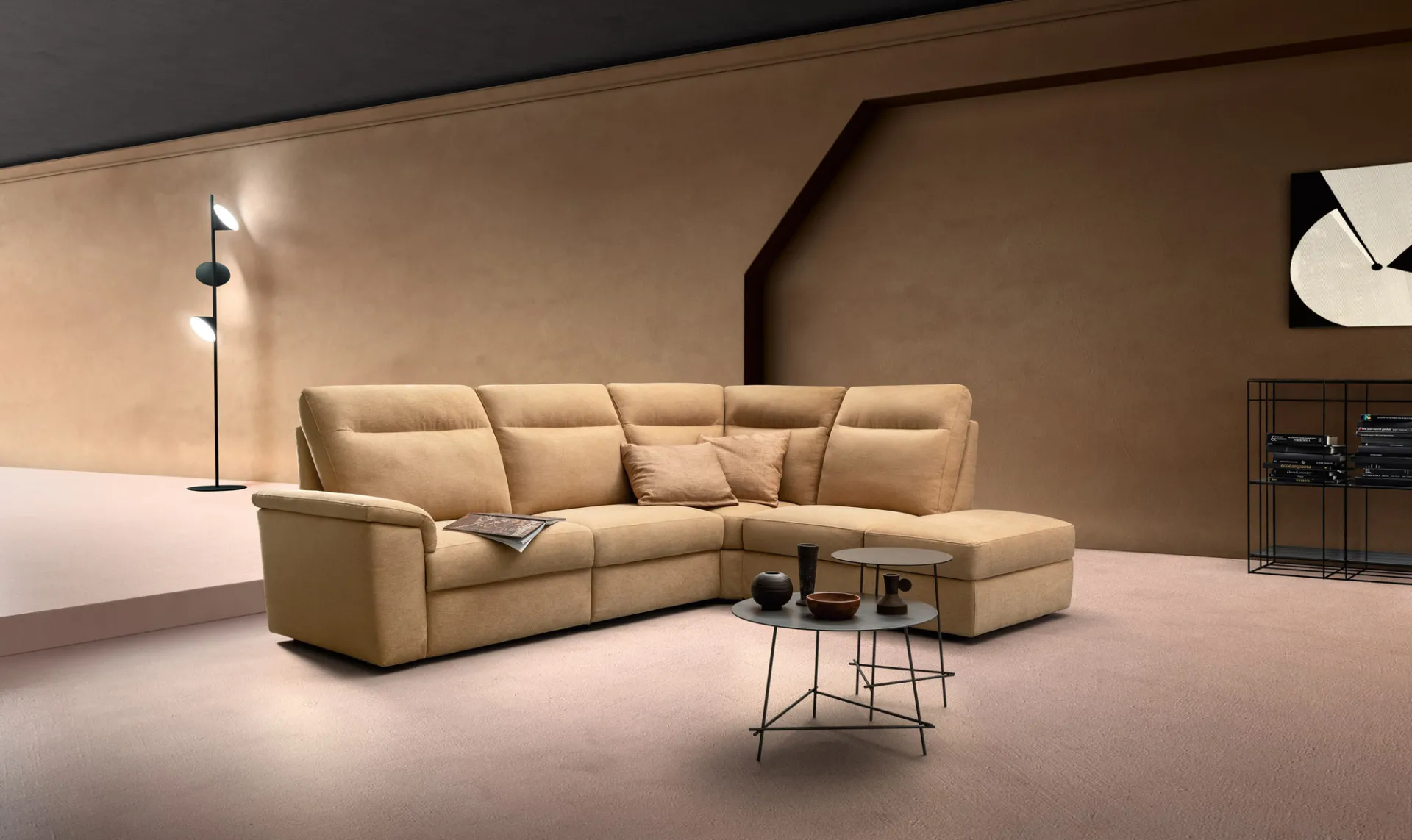 Divano Swing Tender Samoa color cammello ad angolo, accanto a un tavolino rotondo in metallo