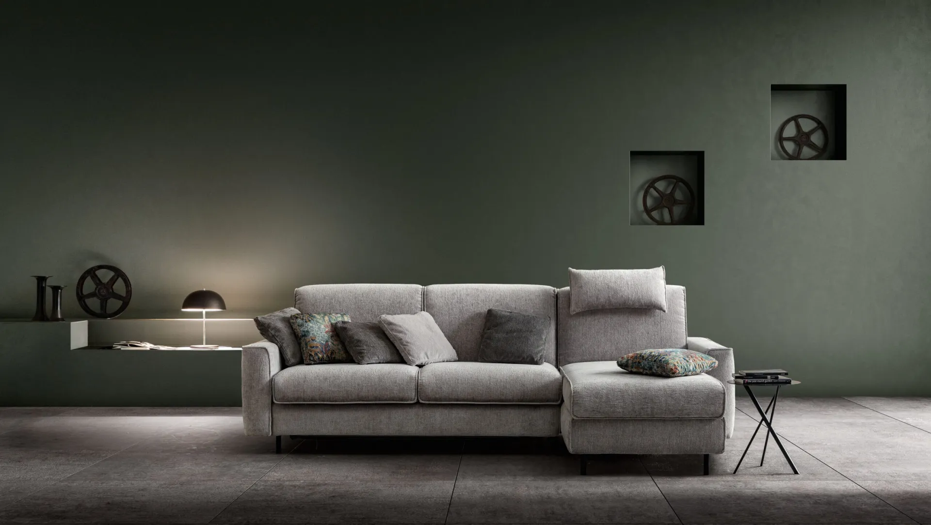 Divano letto Titan Samoa grigio chiaro con penisola, davanti a una parete verde