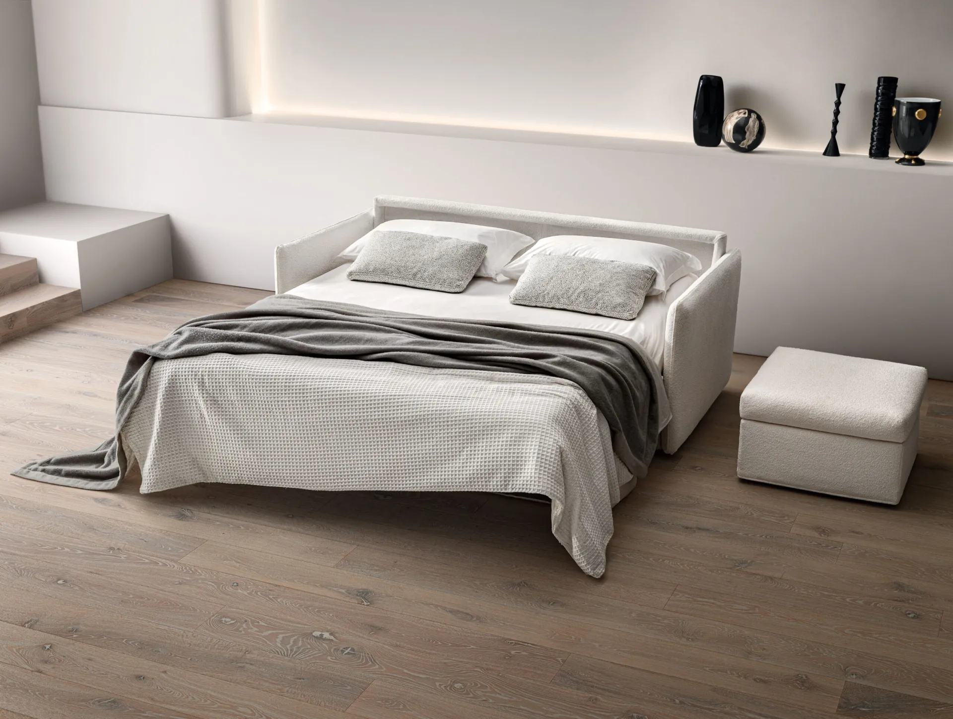 Divano letto Urban Samoa aperto in versione letto matrimoniale accanto al pouf