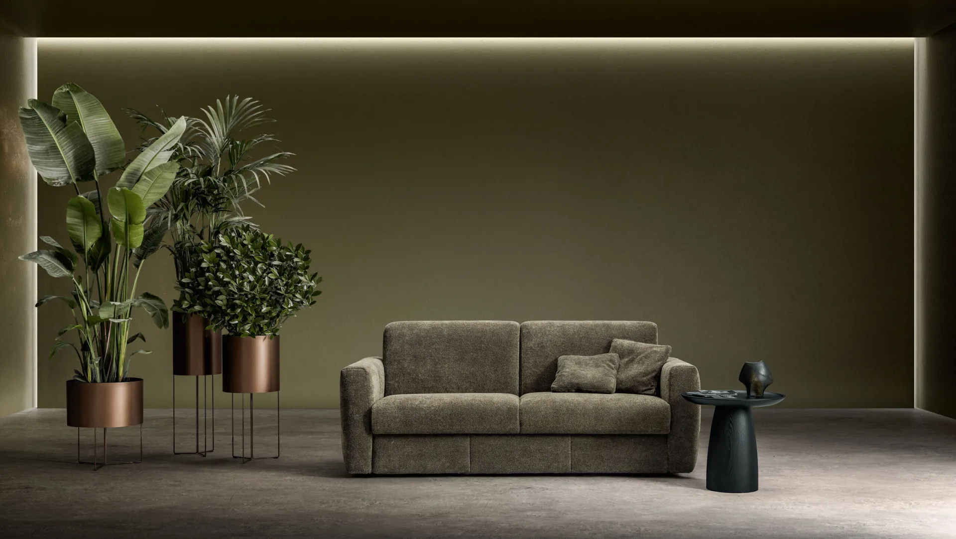 Divano letto Hill Samoa grigio fango a tre posti fra piante in vaso