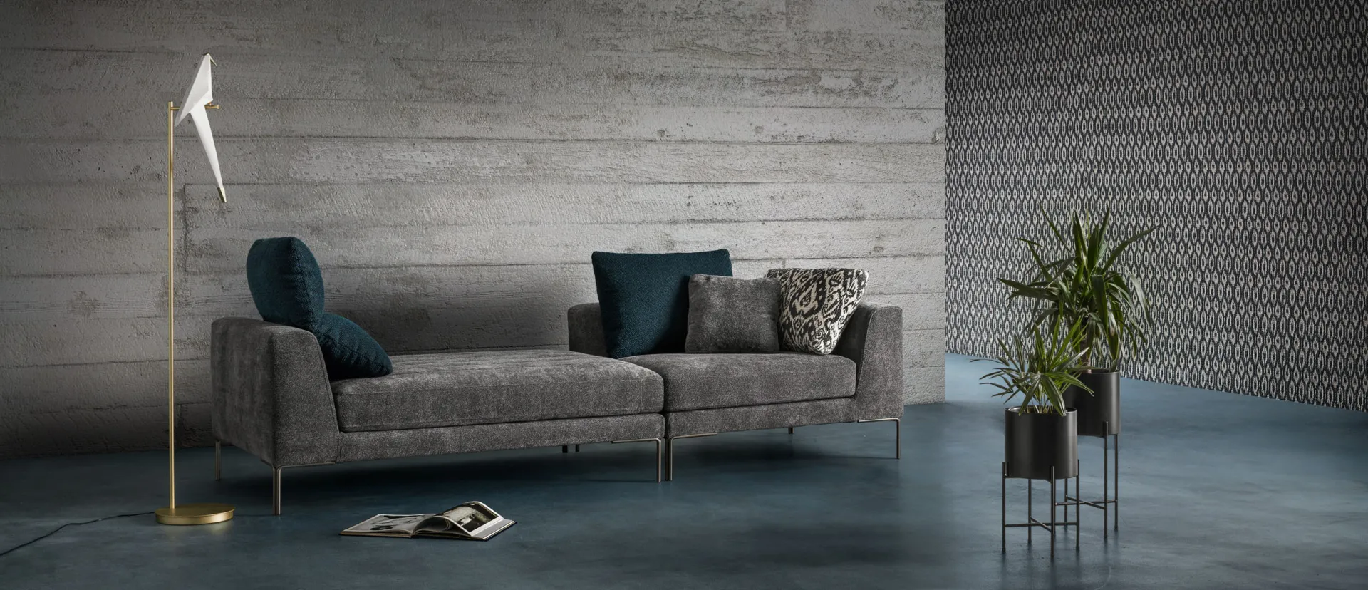 Divano Ares Samoa lineare grigio con cuscini blu e lampada da terra dorata