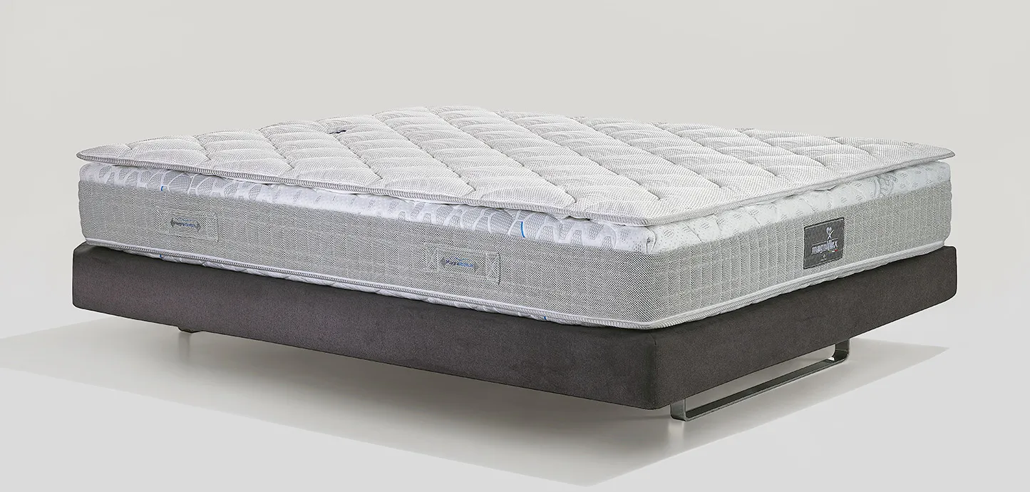Topper MagniCool 3D Magniflex con bordo grigio su un materasso, vista di tre quarti