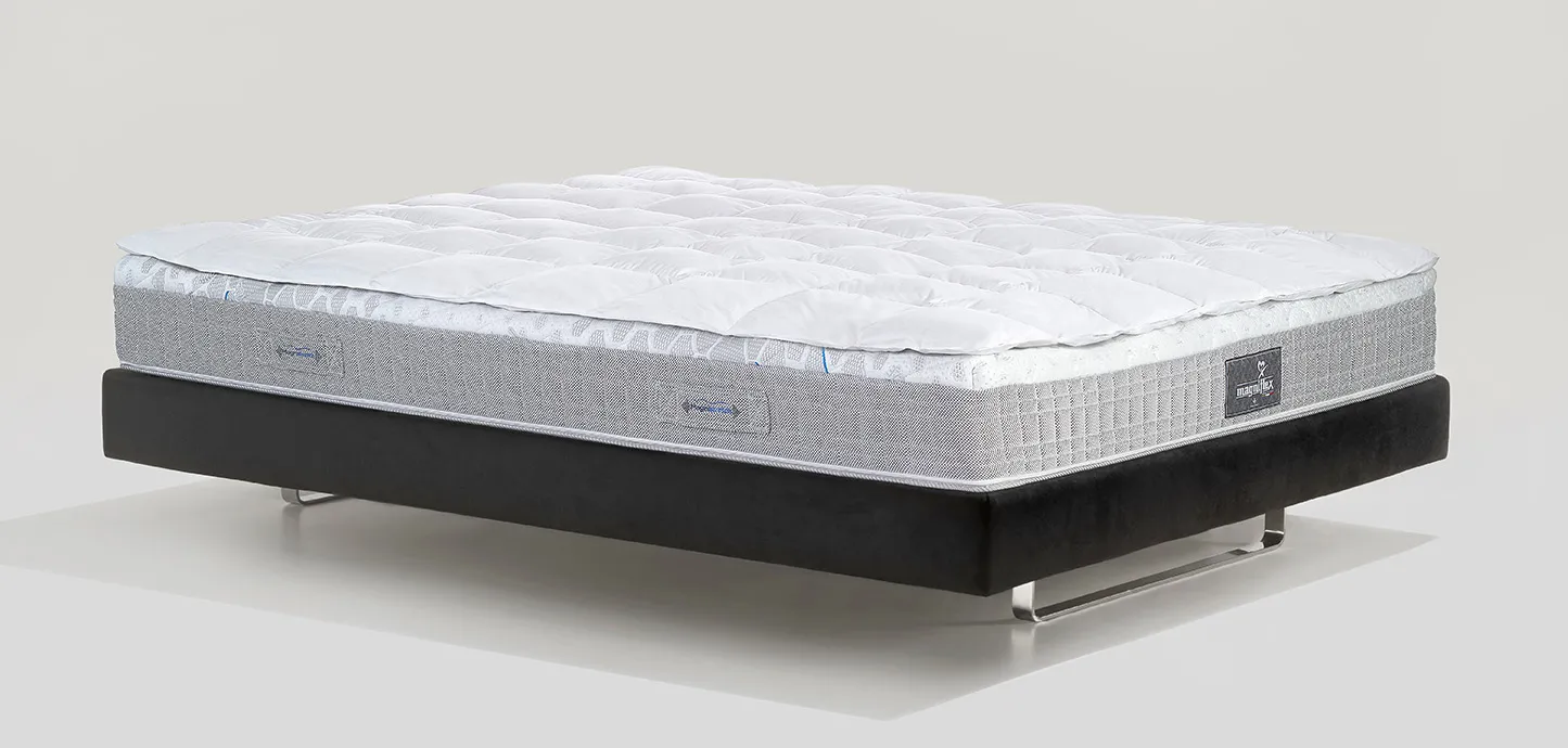 Topper Piuma Magniflex bianco e gonfio su un materasso, vista di tre quarti