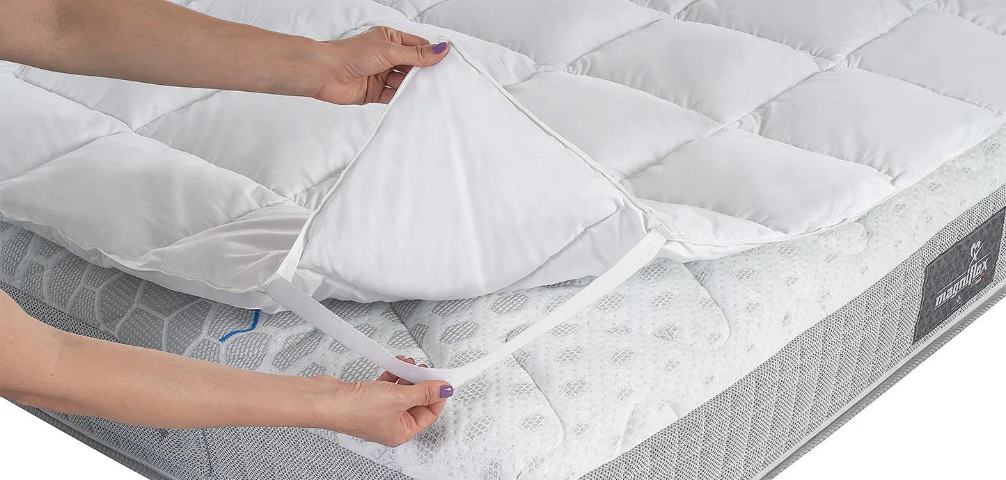 Mani che sollevano un angolo del Topper Piuma Magniflex e ne tendono l'elastico
