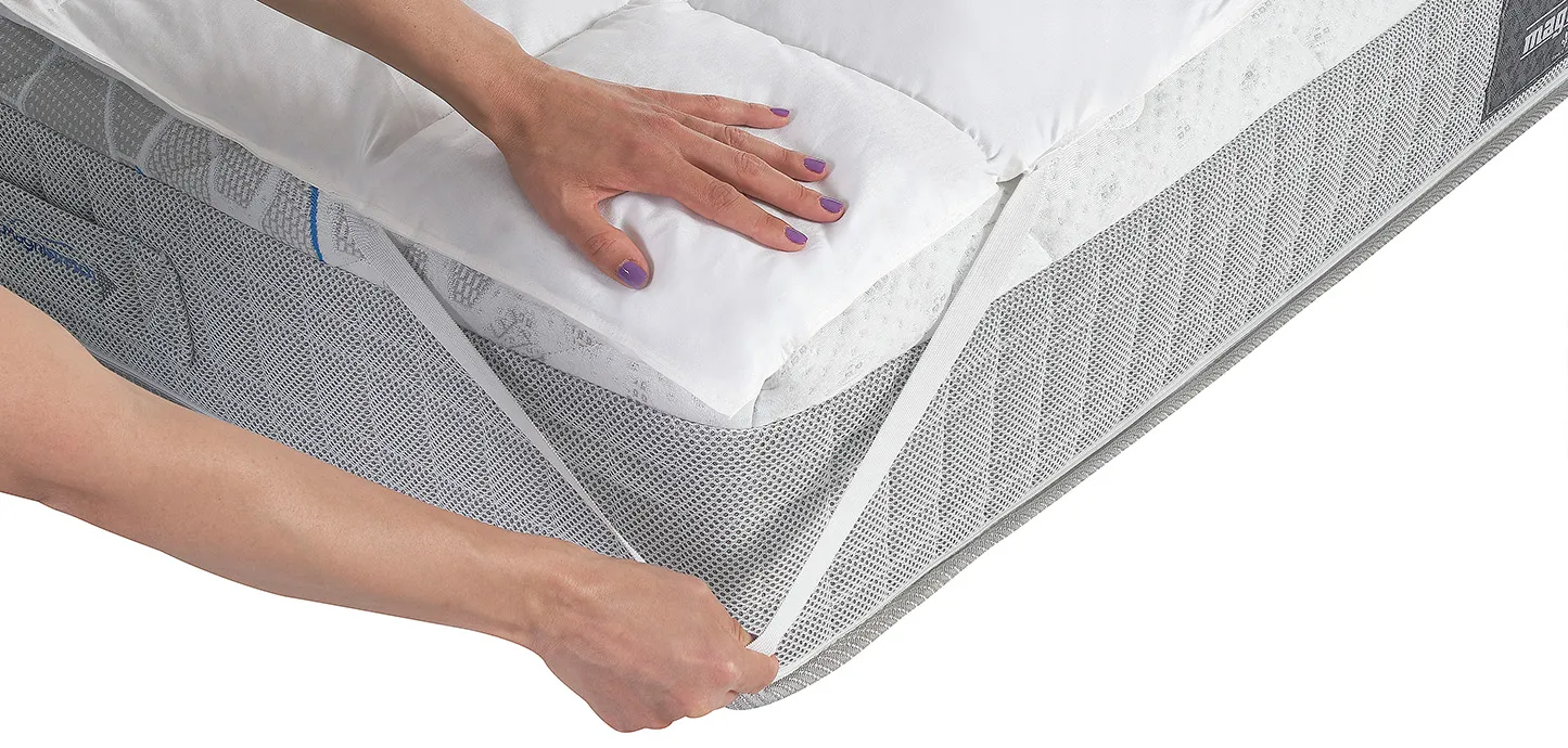 Topper Piuma Magniflex agganciato all'angolo del materasso con una fascia elastica