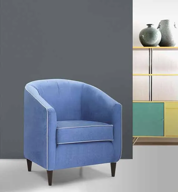 Poltroncina Eva Aerre Divani blu davanti a una parete grigia