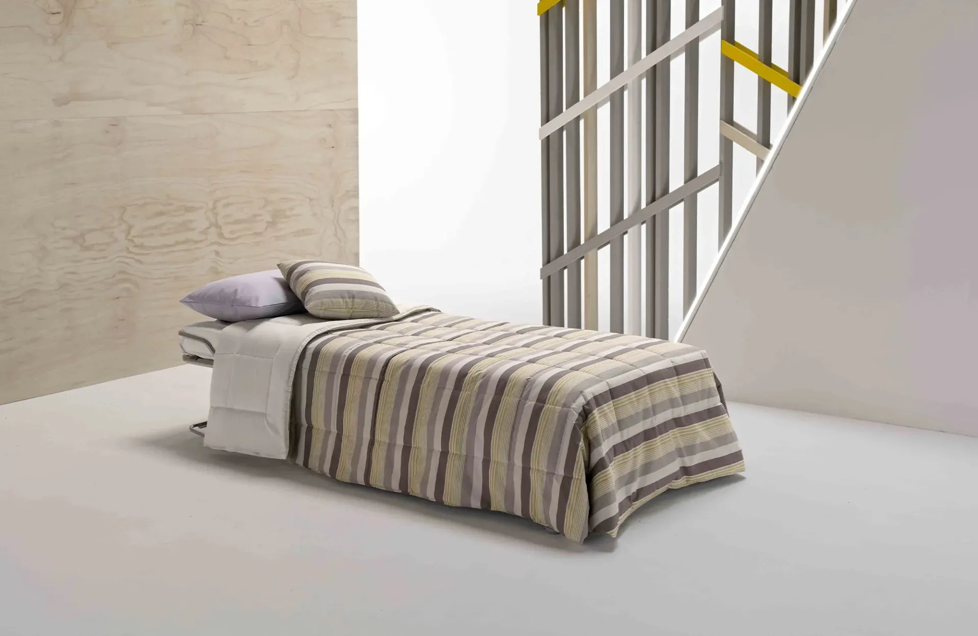 Poltrona letto Oplà Dienne aperta come letto singolo con copriletto a righe