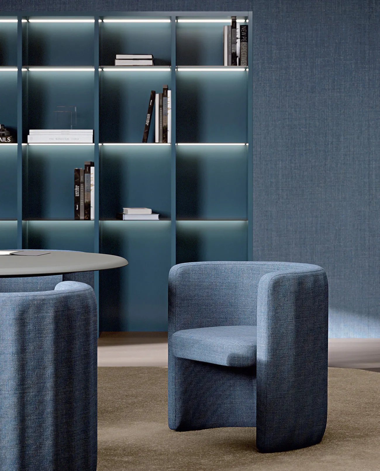 Poltroncina Sabree Frezza blu davanti a una libreria illuminata